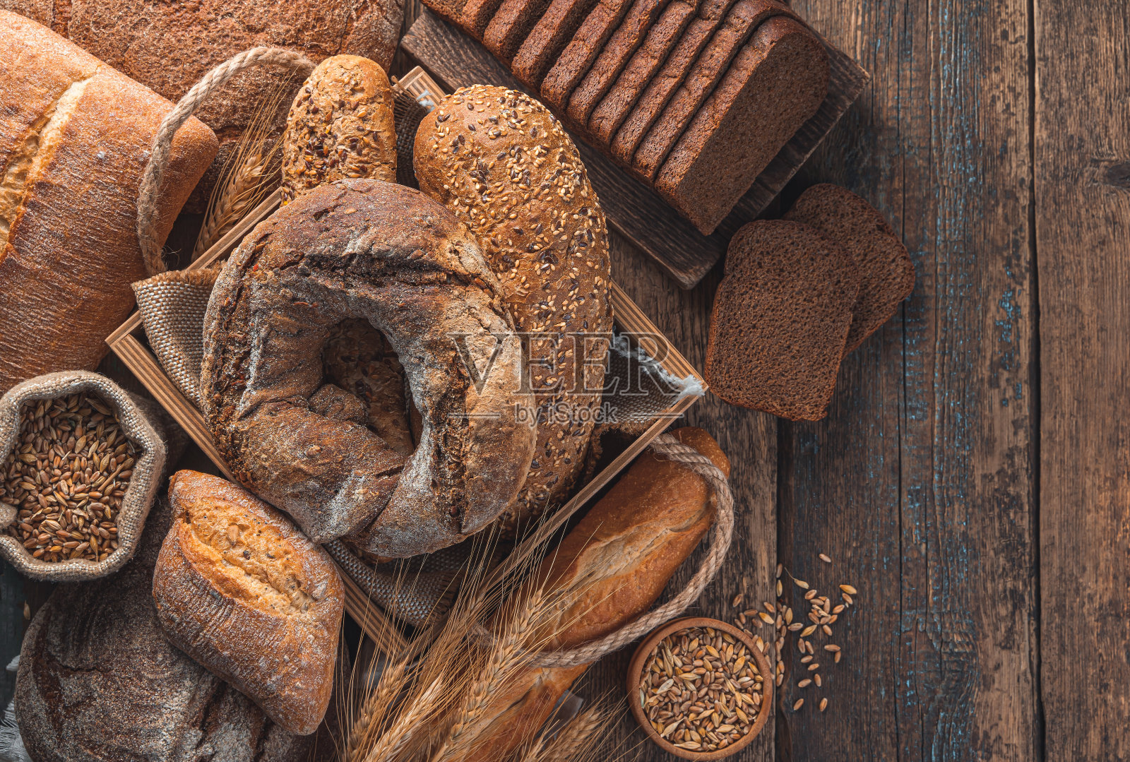 木制背景上的不同类型的面包。面包店的产品照片摄影图片