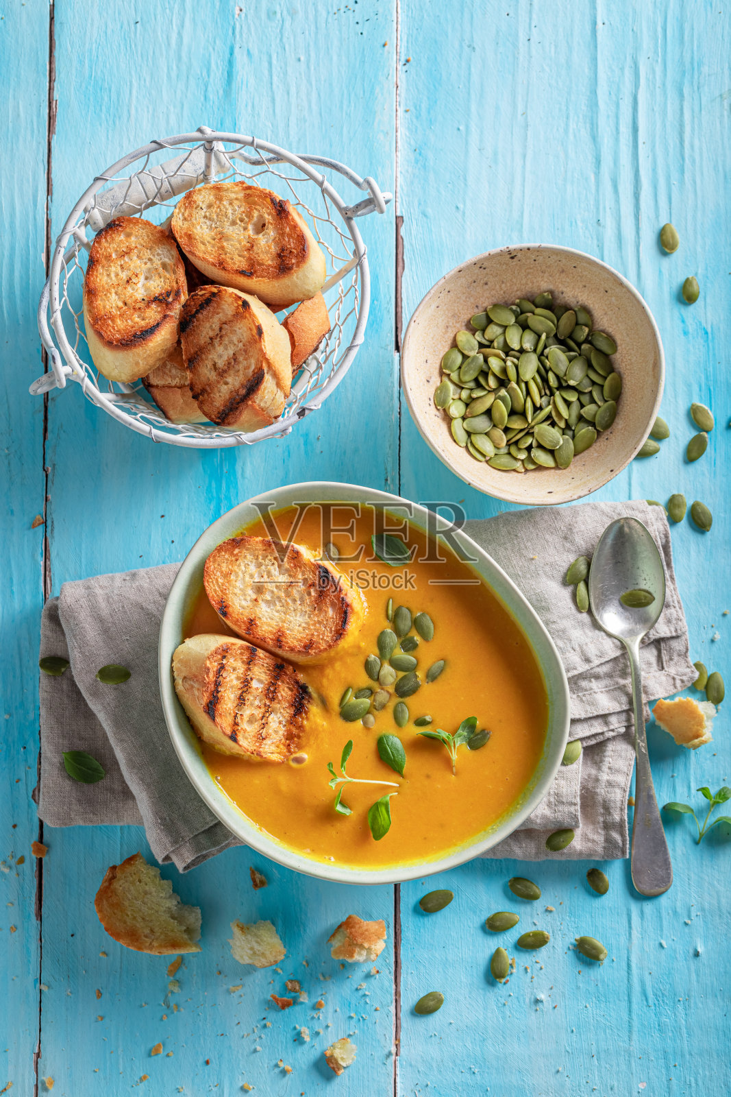 黄南瓜汤配烤面包和南瓜子。照片摄影图片