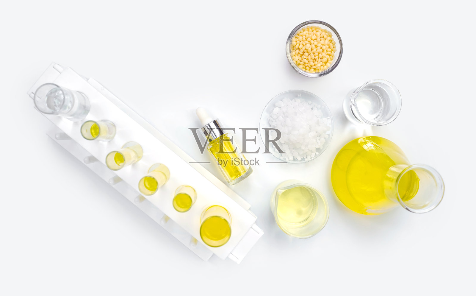 化妆品化学成分白色实验室桌子上。小烛蜡，微晶蜡，黄色化妆品(油)，氯化镍液和酒精。照片摄影图片