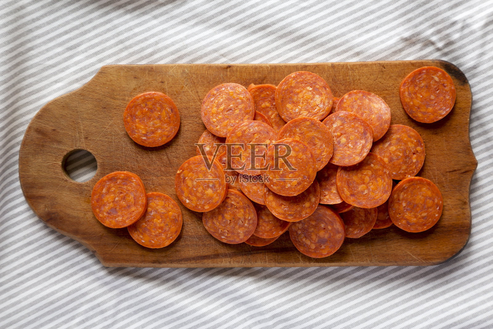 意大利辣香肠片在粗糙的木板上布，俯视图。平铺，在头上，从上面。照片摄影图片