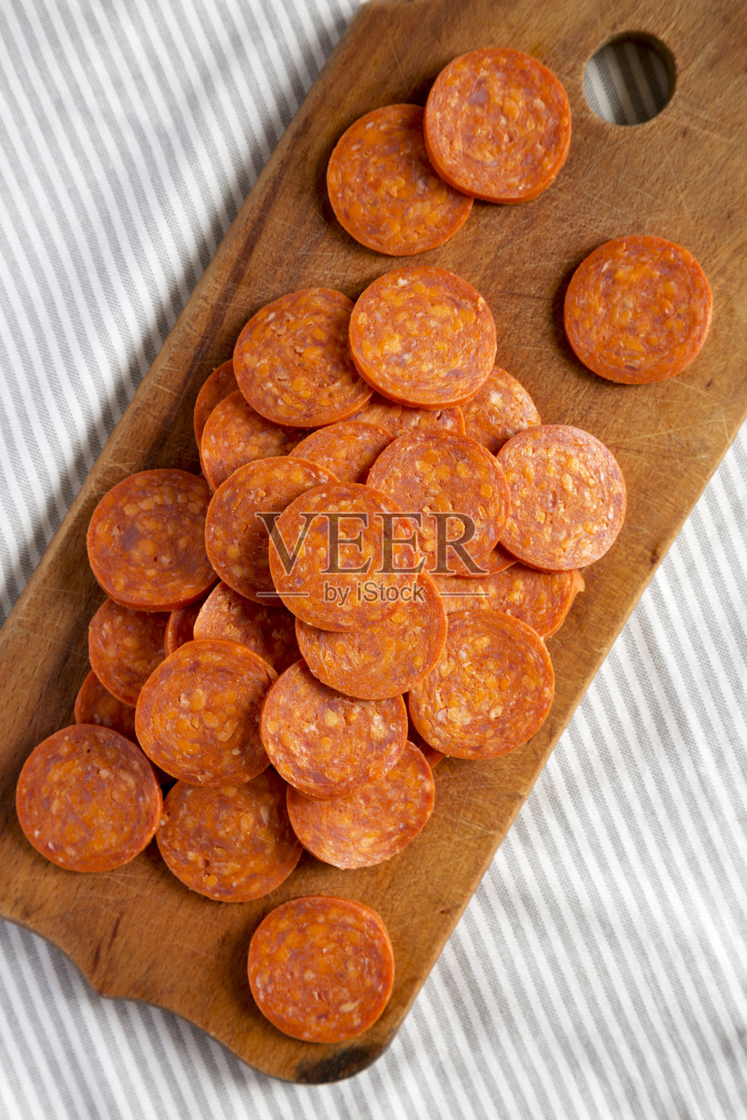 意大利辣香肠片在一块粗糙的木板上布，从上面看。平铺，头顶，俯视图。照片摄影图片