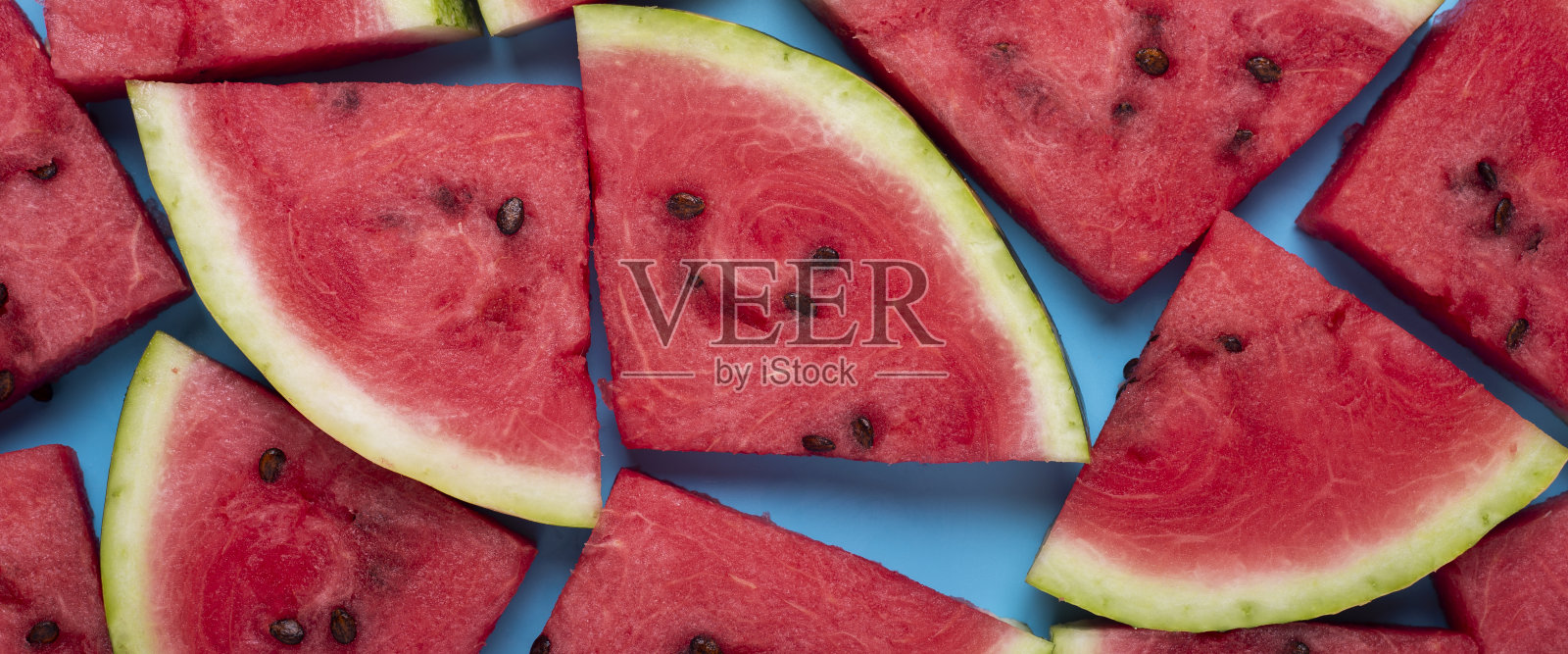 背景是一片多汁的红色西瓜，背景是蓝色的。俯视图，平铺。横幅照片摄影图片