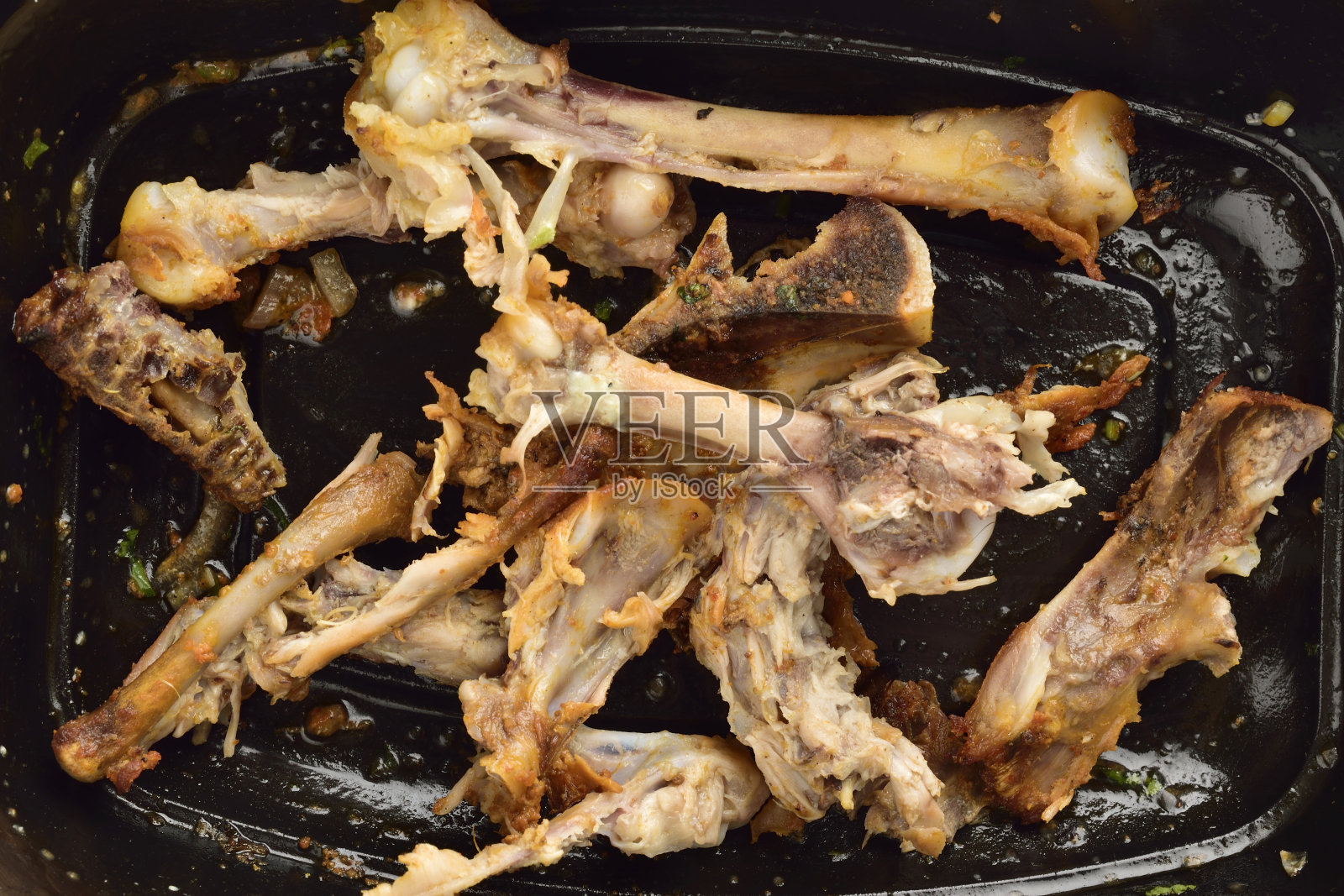 特写剩鸡骨头在黑色盘子照片摄影图片