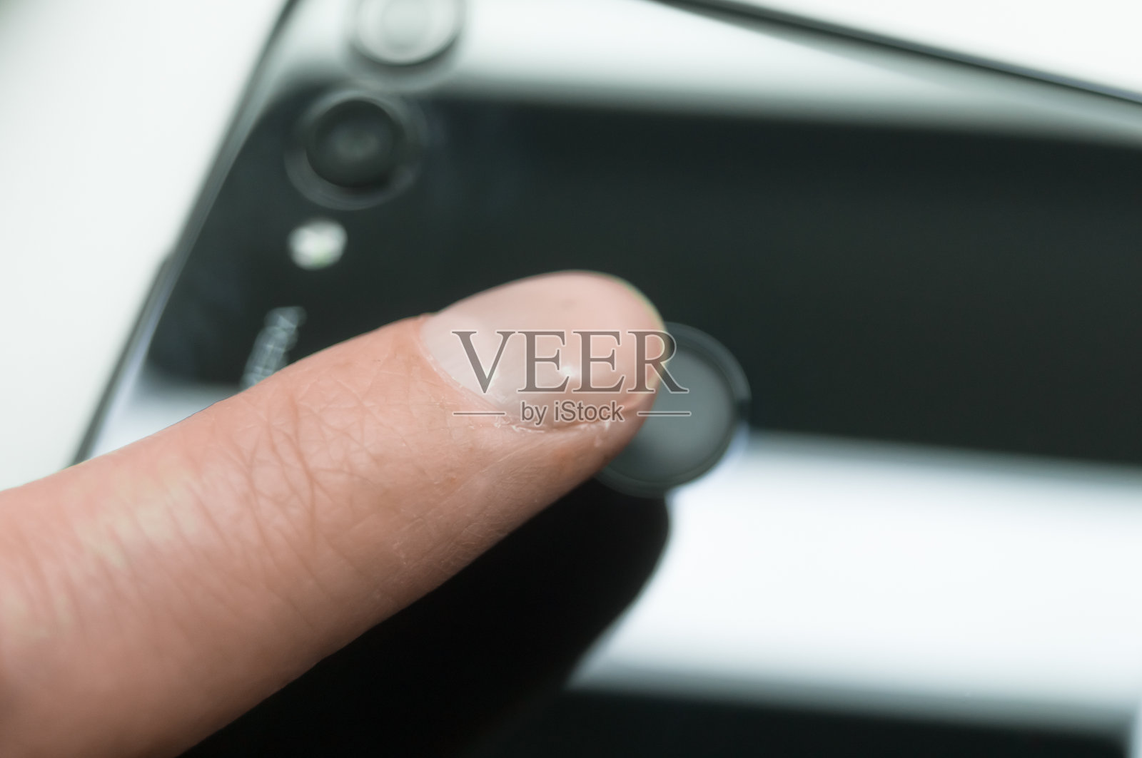 触摸智能手机背面的指纹传感器。手机解锁系统。有选择性的重点照片摄影图片