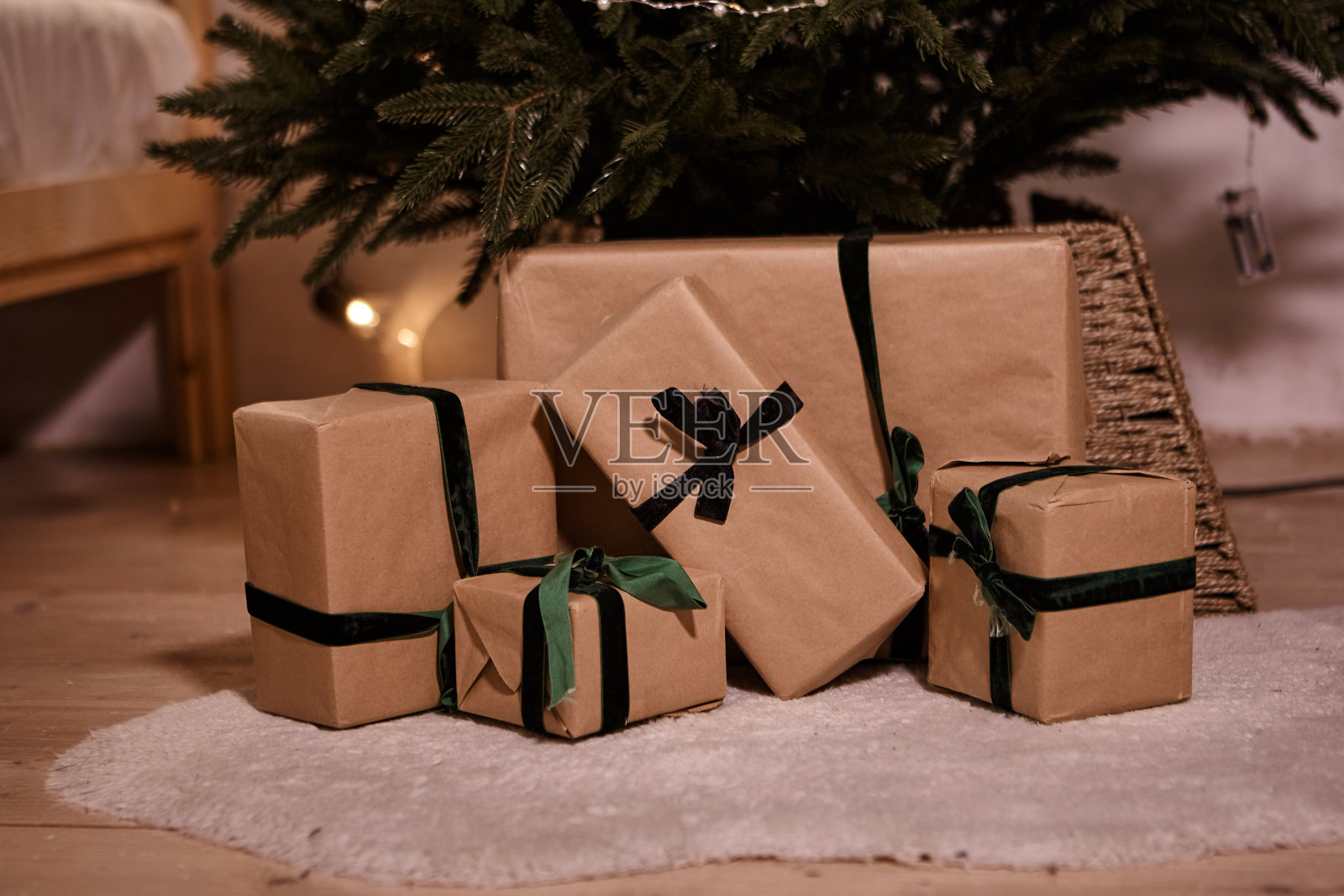 漂亮的圣诞礼品盒在房间的冷杉树附近的地板上。白色圣诞树照片摄影图片