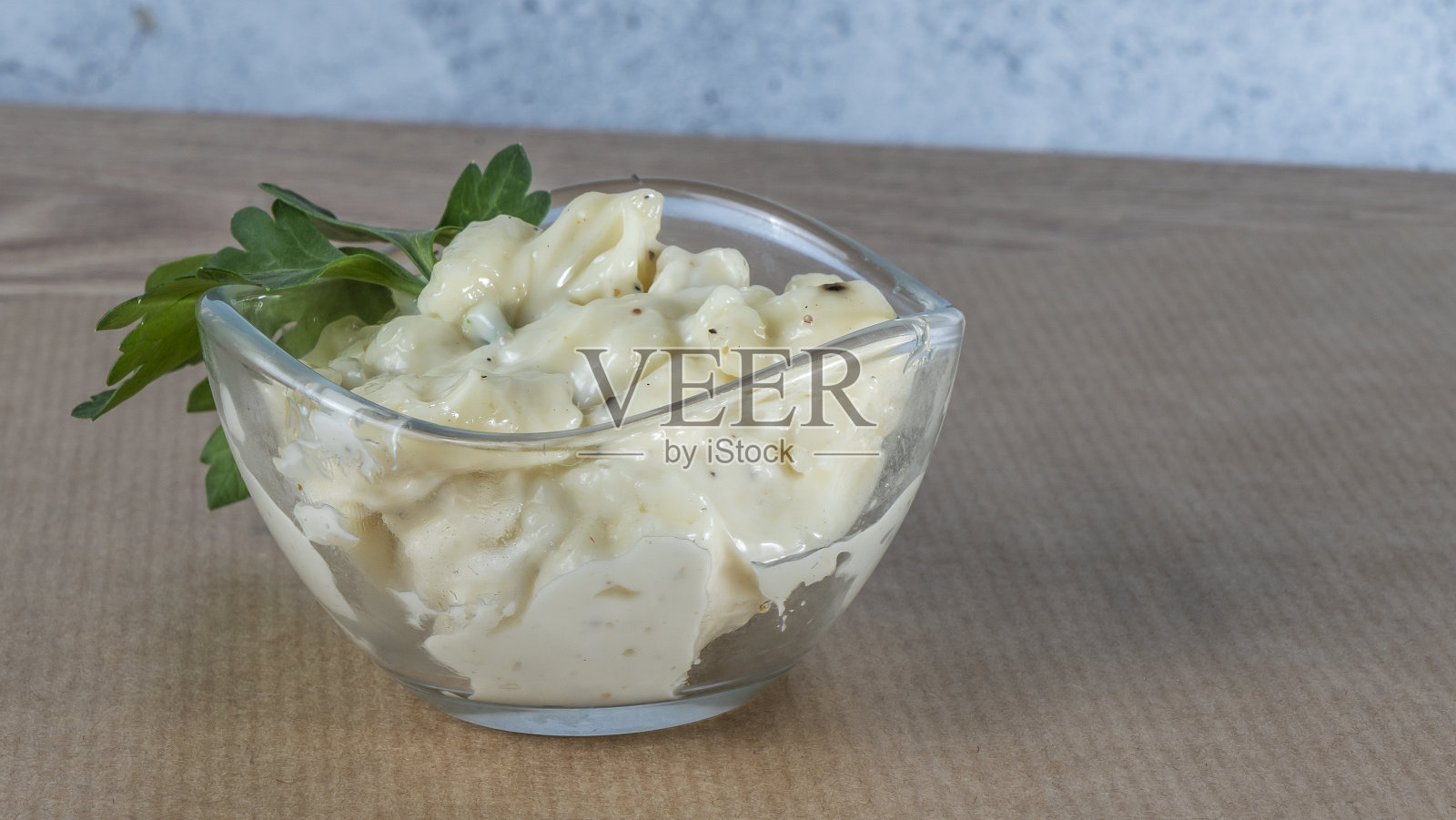 在羊皮纸上自制鞑靼酱的俯视图。一碗新鲜的大蒜蘸酱。照片摄影图片