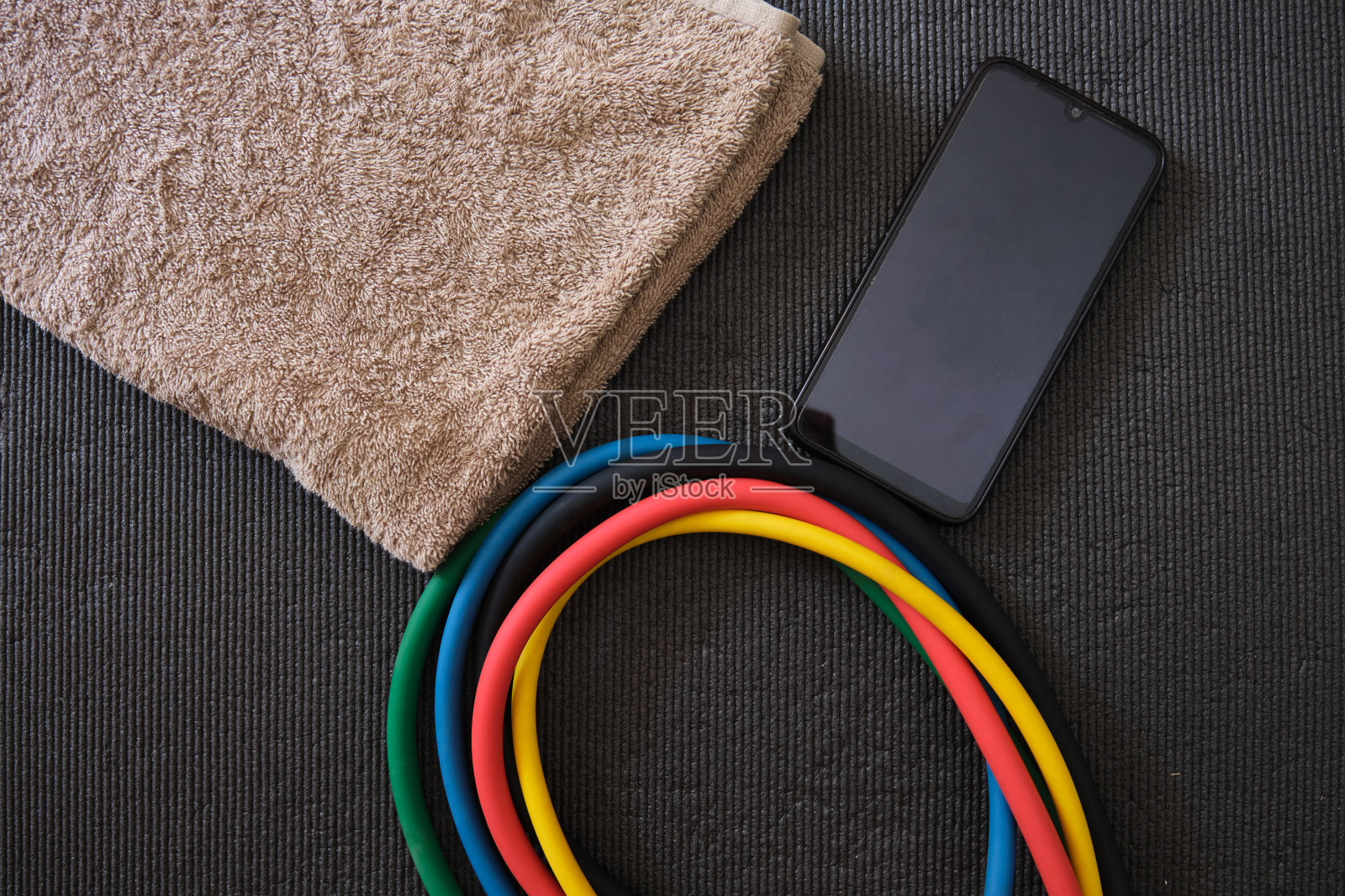 用不同强度和颜色的橡皮筋在家里的健身垫上做肌肉锻炼。健康的生活方式，在家锻炼。培训设备照片摄影图片