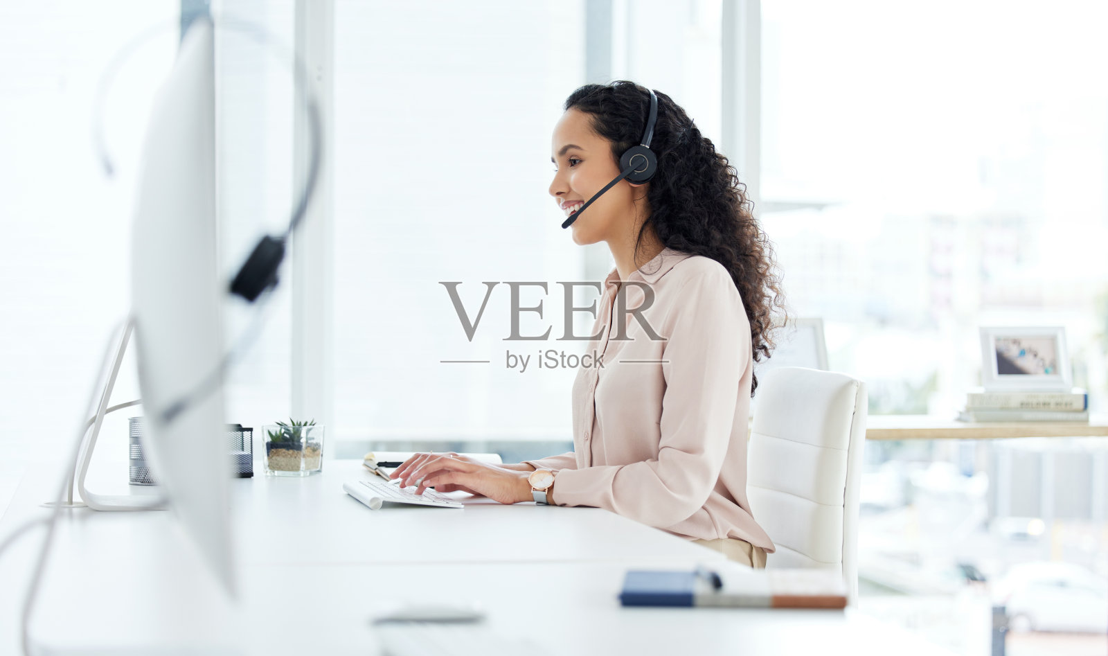 一个年轻的呼叫中心代理在办公室的电脑上工作照片摄影图片