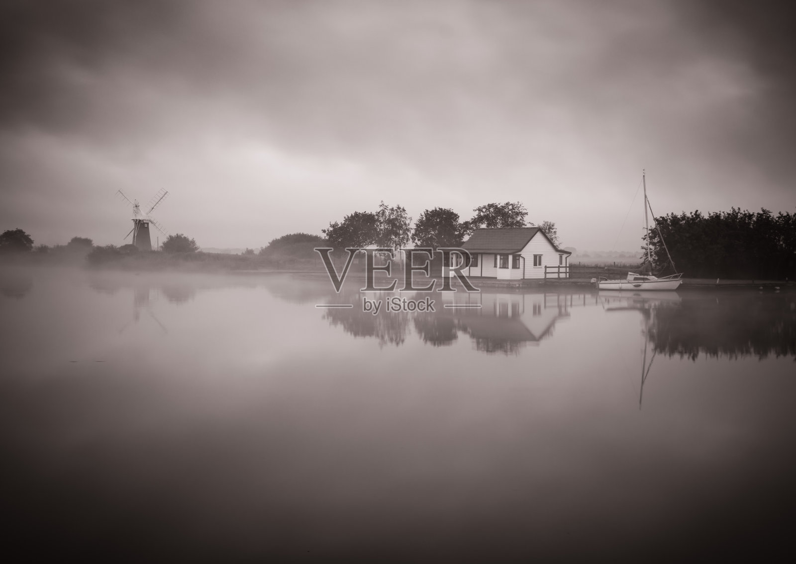 雾蒙蒙的河，单风泵和木屋倒映在河中照片摄影图片
