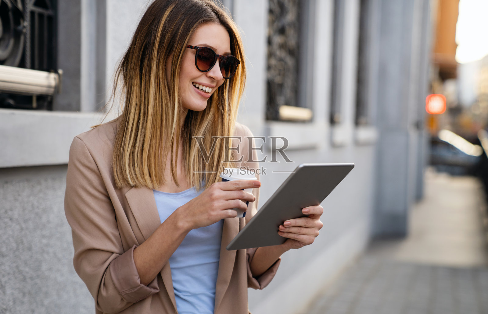 在城市背景的快速休息期间，一个成功的女人使用数码平板电脑的肖像照片摄影图片