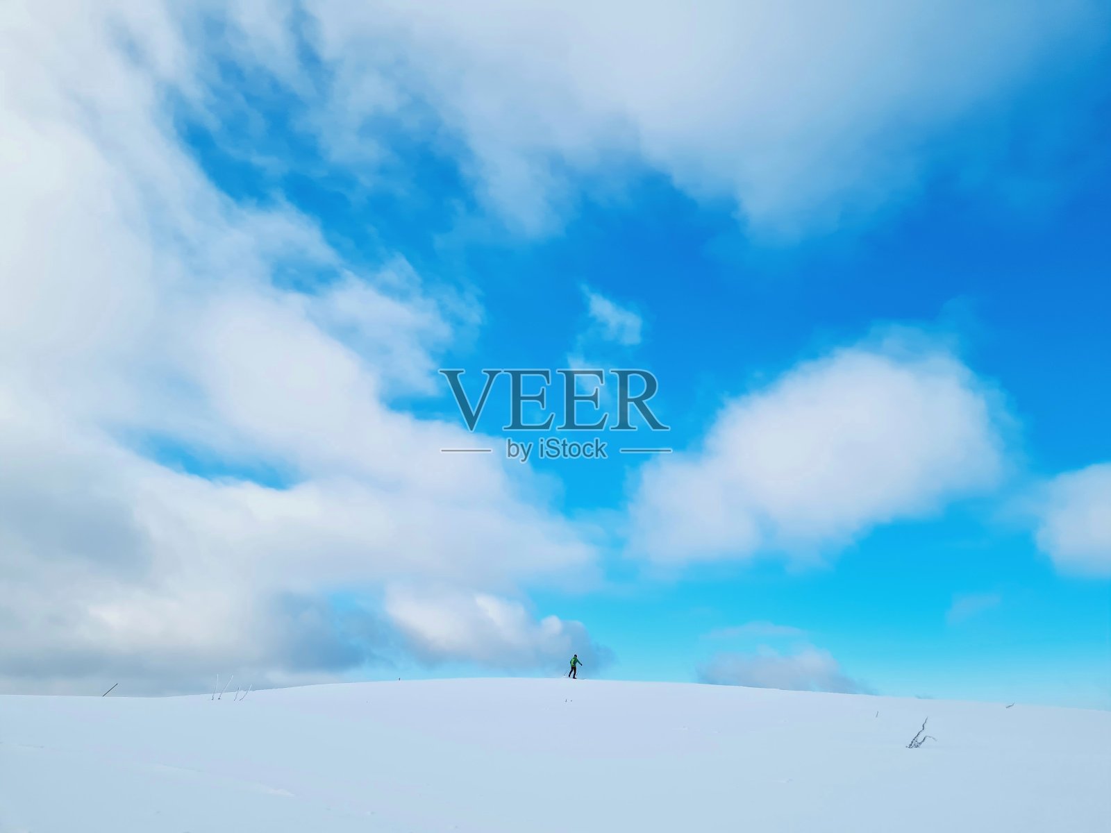 滑雪者在远处的雪山上照片摄影图片