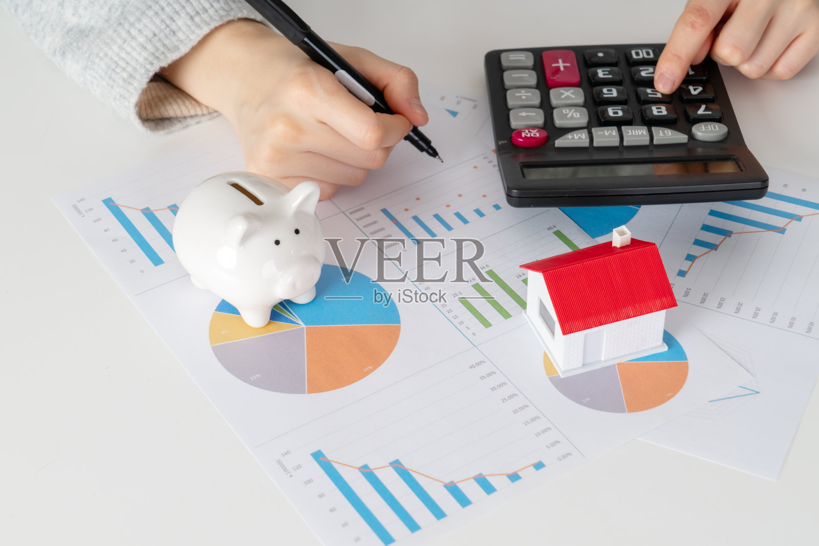 房地产金融的概念，女人拿着钥匙，房子模型和钱罐照片摄影图片