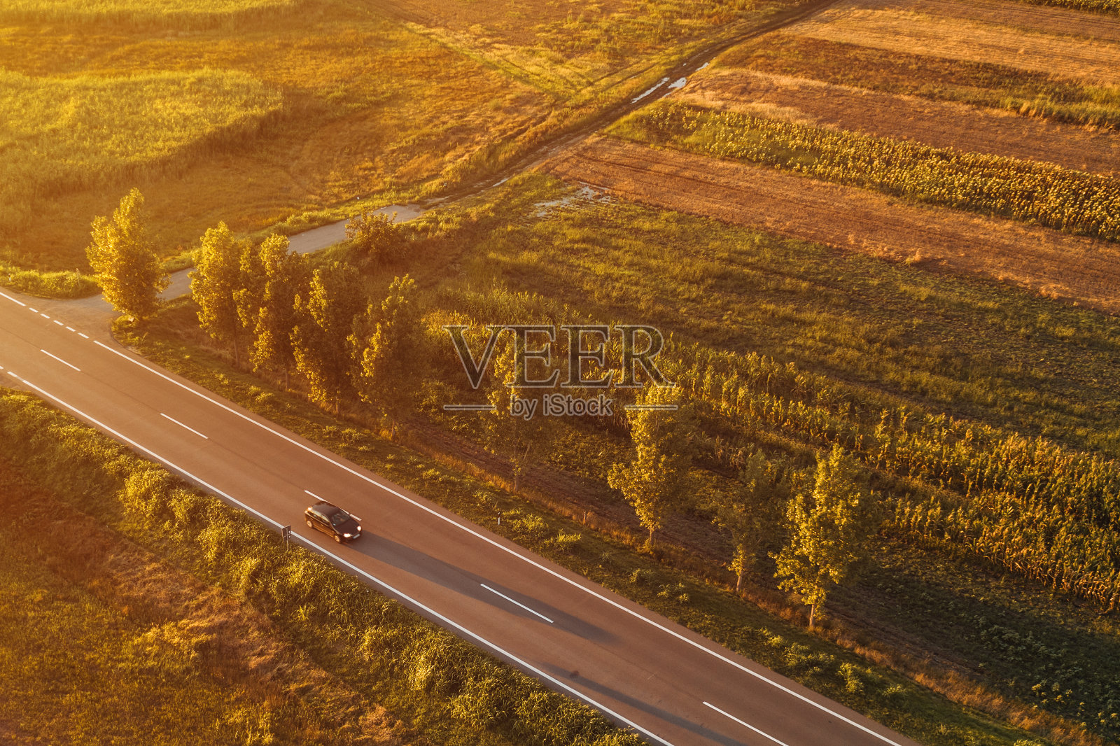 无人机拍摄的黑色轿车在夏日夕阳下行驶在路上照片摄影图片