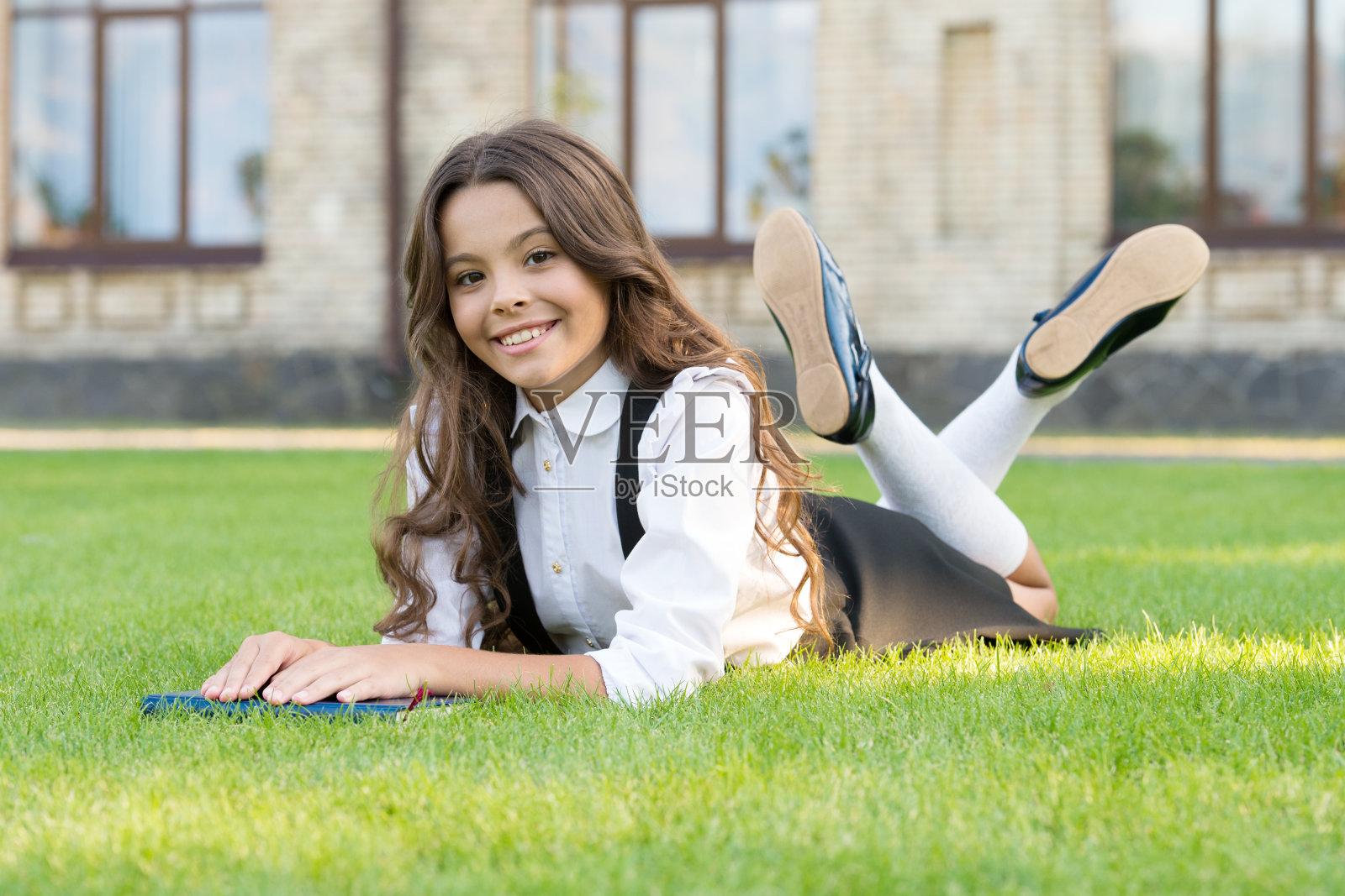 读的学校。快乐的小学生在绿色的草地上放松。小女孩喜欢上学。9月1日。知识的一天。欢迎回到学校照片摄影图片