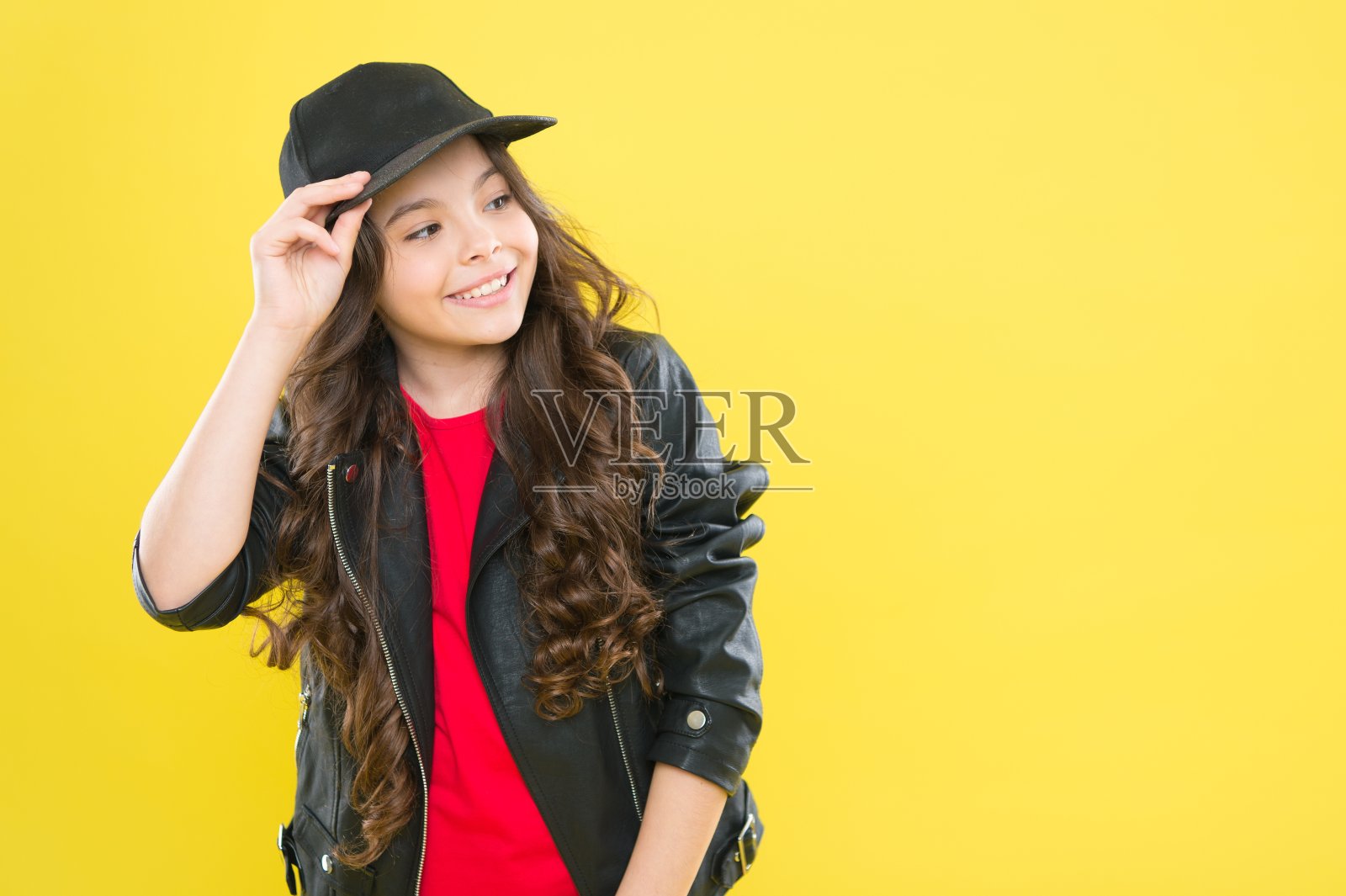 在时尚沙龙给她穿上最好的衣服。快乐的孩子固定帽子黄色的背景。儿童穿的。休闲风格。新潮时尚。现代streetwear。发廊，复印空间照片摄影图片