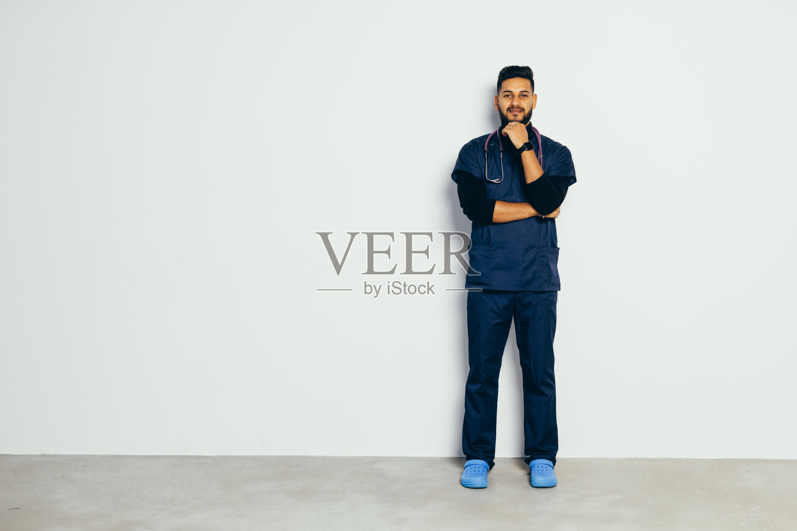 年轻英俊的印度男子医生在灰色背景下照片摄影图片