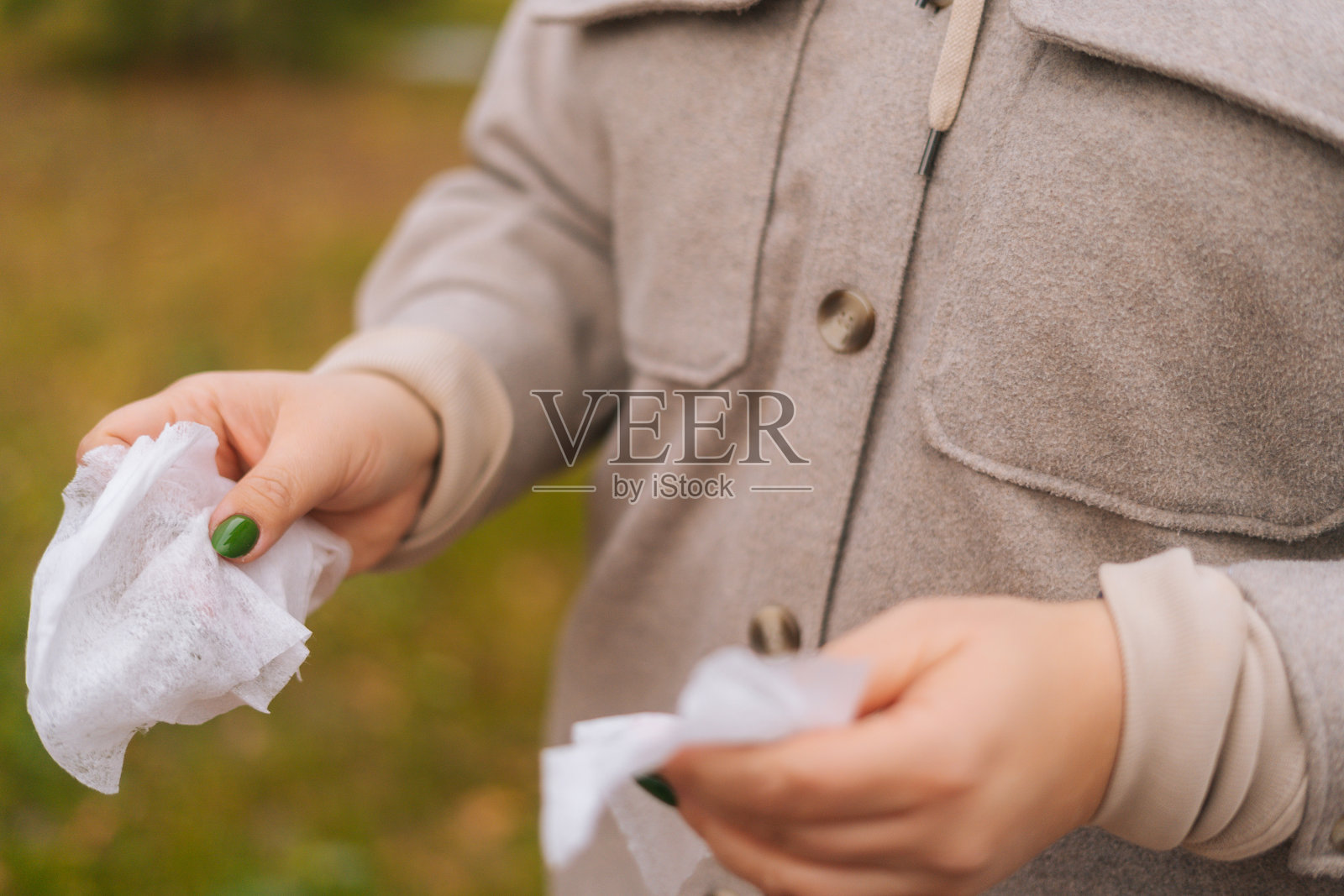 特写镜头，无法辨认的妇女持有抗菌湿巾清洁和消毒的手在户外。照片摄影图片