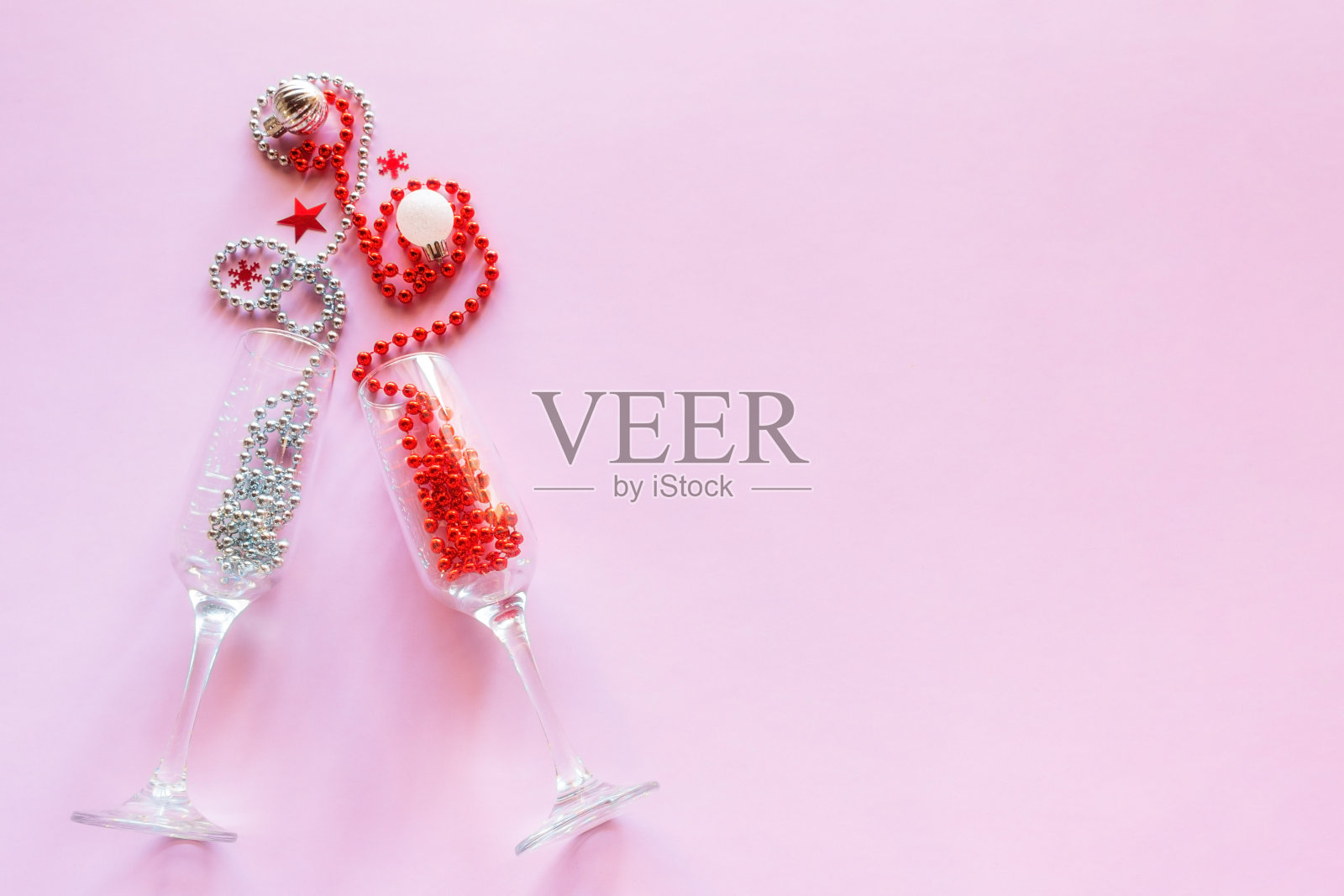 香槟杯与珠子和圣诞树装饰在粉红色的背景与地方的文字祝新年圣诞快乐照片摄影图片