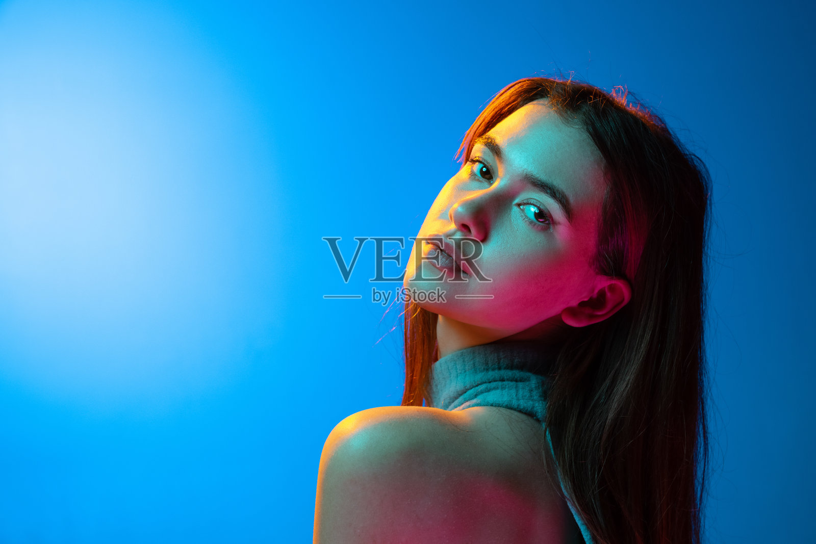 美丽的女性半身肖像孤立在蓝色工作室背景霓虹灯。人类的情感、面部表情概念照片摄影图片