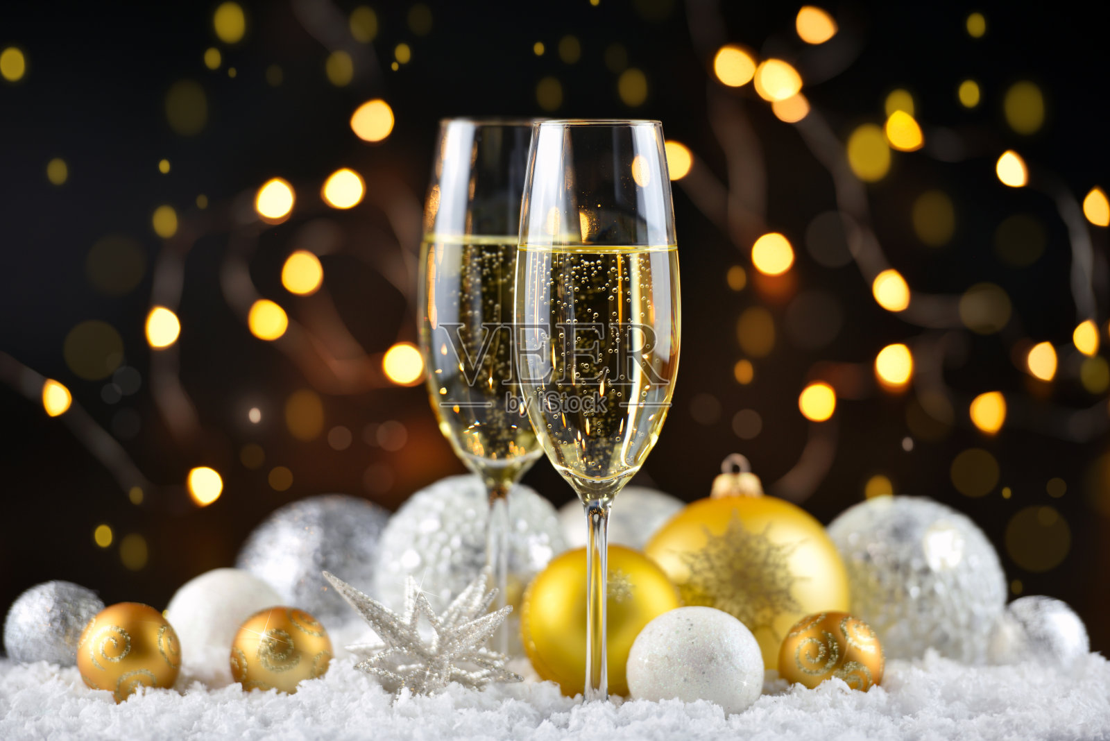 在黑暗的节日背景下，两只香槟酒杯和雪上的圣诞装饰。新年快乐。照片摄影图片