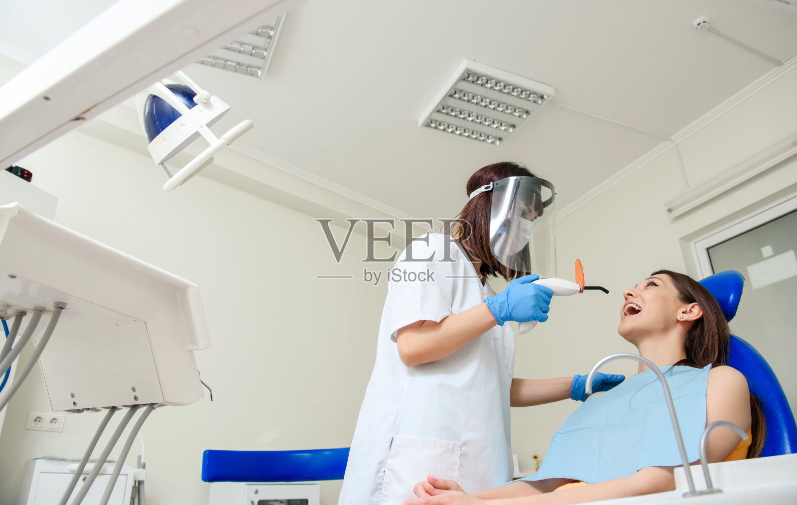 牙科医生正在使用光致聚合物光完成牙科补牙治疗。照片摄影图片