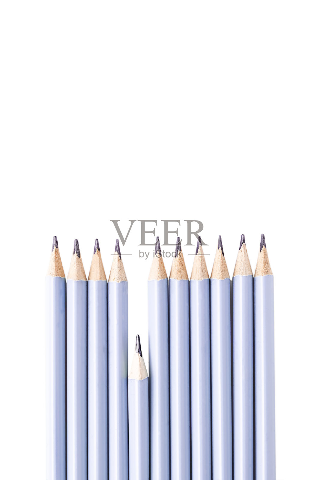 在白色的背景上，一支铅笔从一系列相同的简单石墨铅笔中脱颖而出。垂直背景、孤立。照片摄影图片
