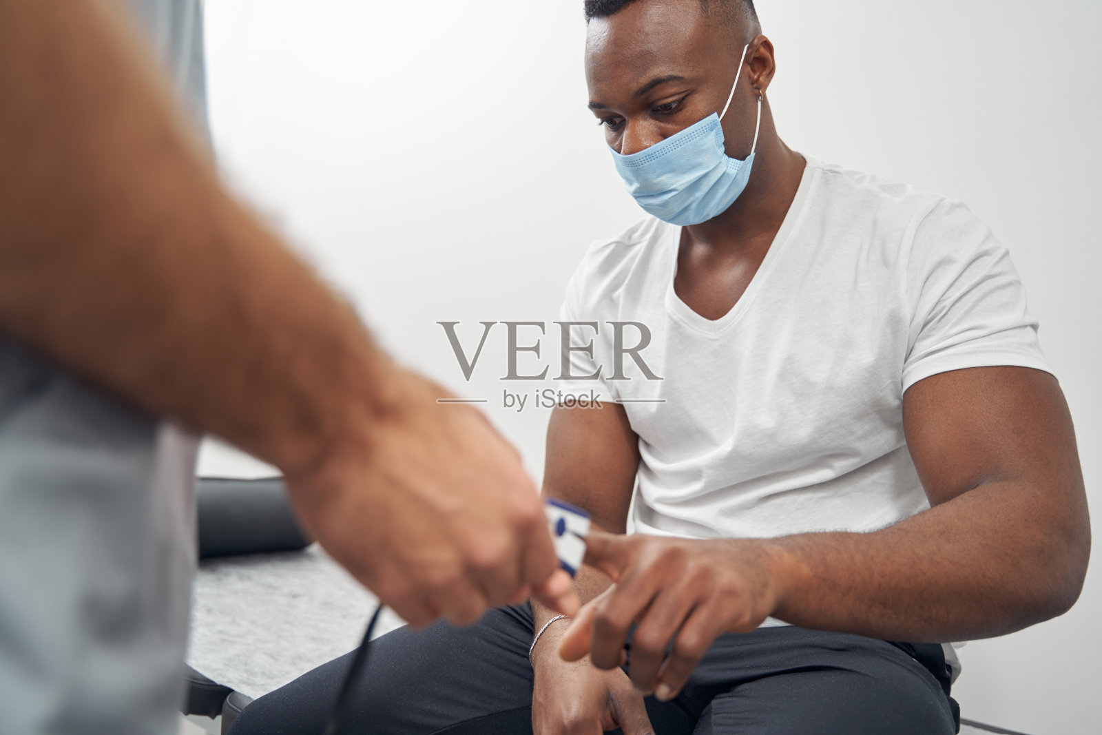 医生在测量年轻人血液中的氧饱和度照片摄影图片