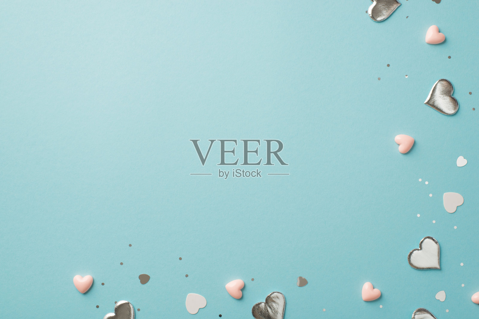 俯视图照片的情人节装饰银和粉红色的心纸屑和亮片在孤立的粉彩蓝色背景与空空间照片摄影图片