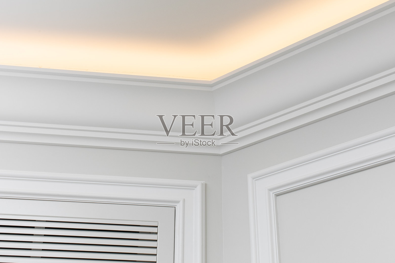 现代室内装修的特写细节。有棱角的天花板踢脚板由经典的白色造型制成，内置LED天花板照明。照片摄影图片