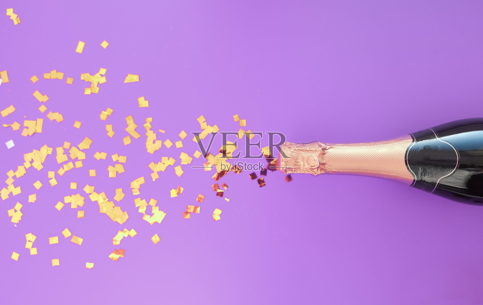 一瓶用五彩纸屑点缀在时尚紫色背景上的香槟照片摄影图片