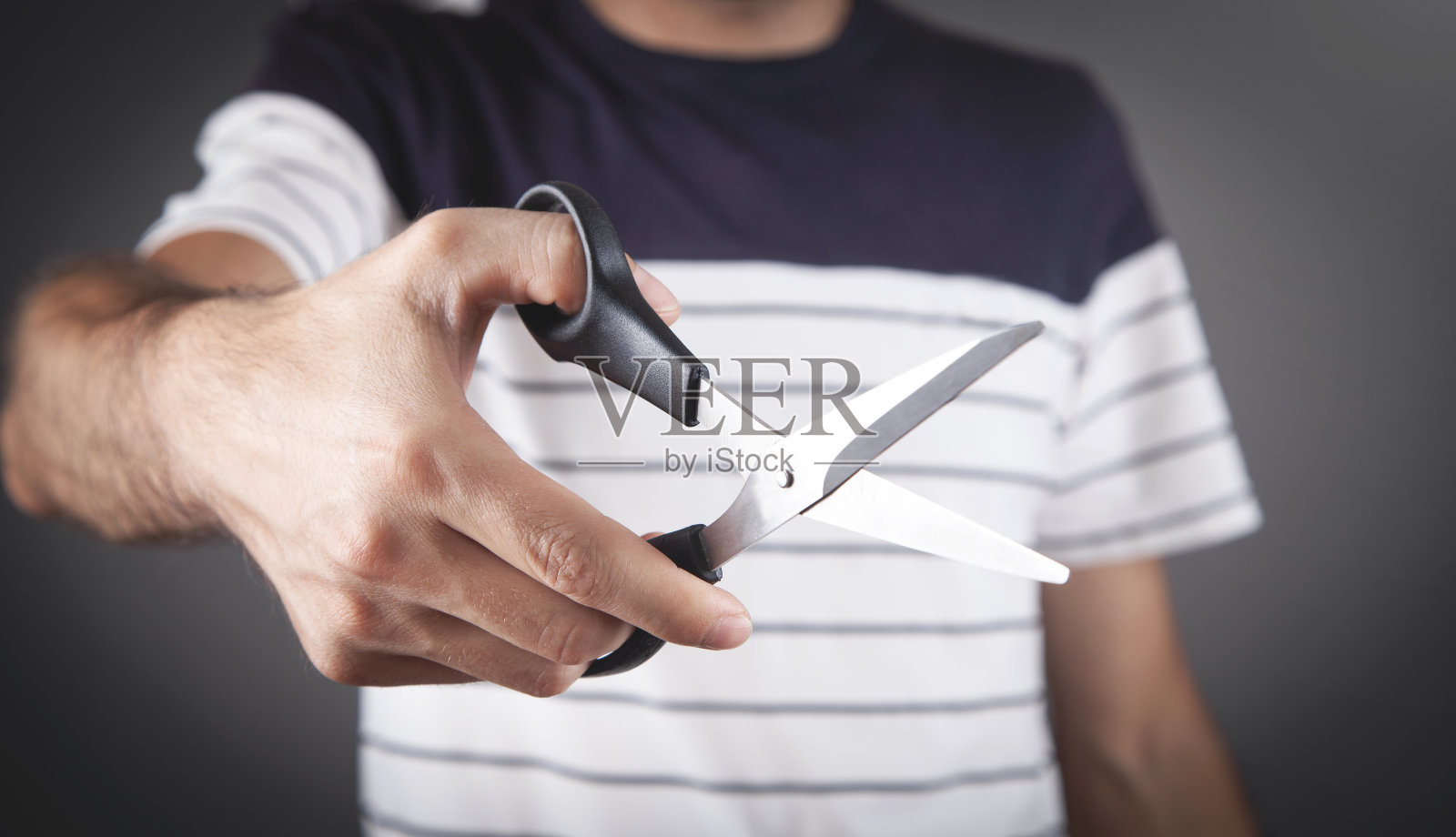 男性手里拿着一把黑色的剪刀。照片摄影图片