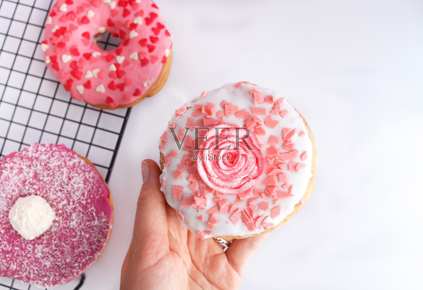 可爱的粉色甜甜圈与玫瑰装饰在白色的背景照片摄影图片