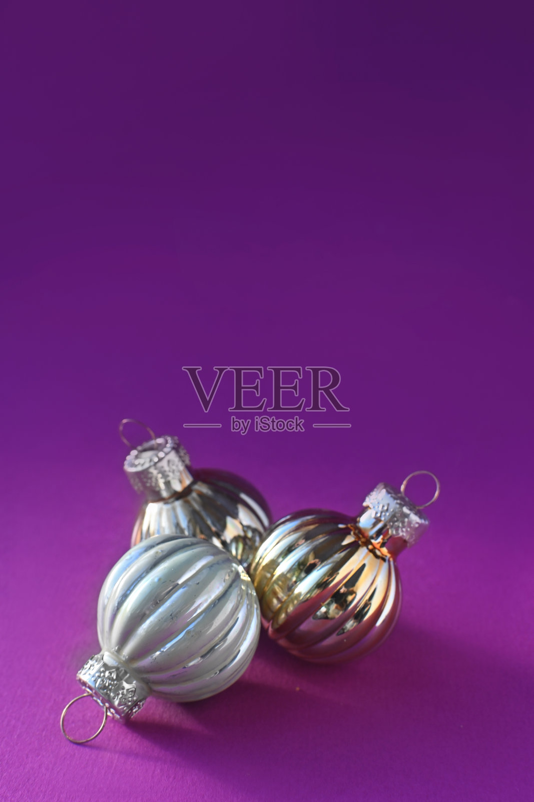 紫色背景上明亮的银色圣诞球。圣诞快乐，恭贺新禧。垂直照片摄影图片