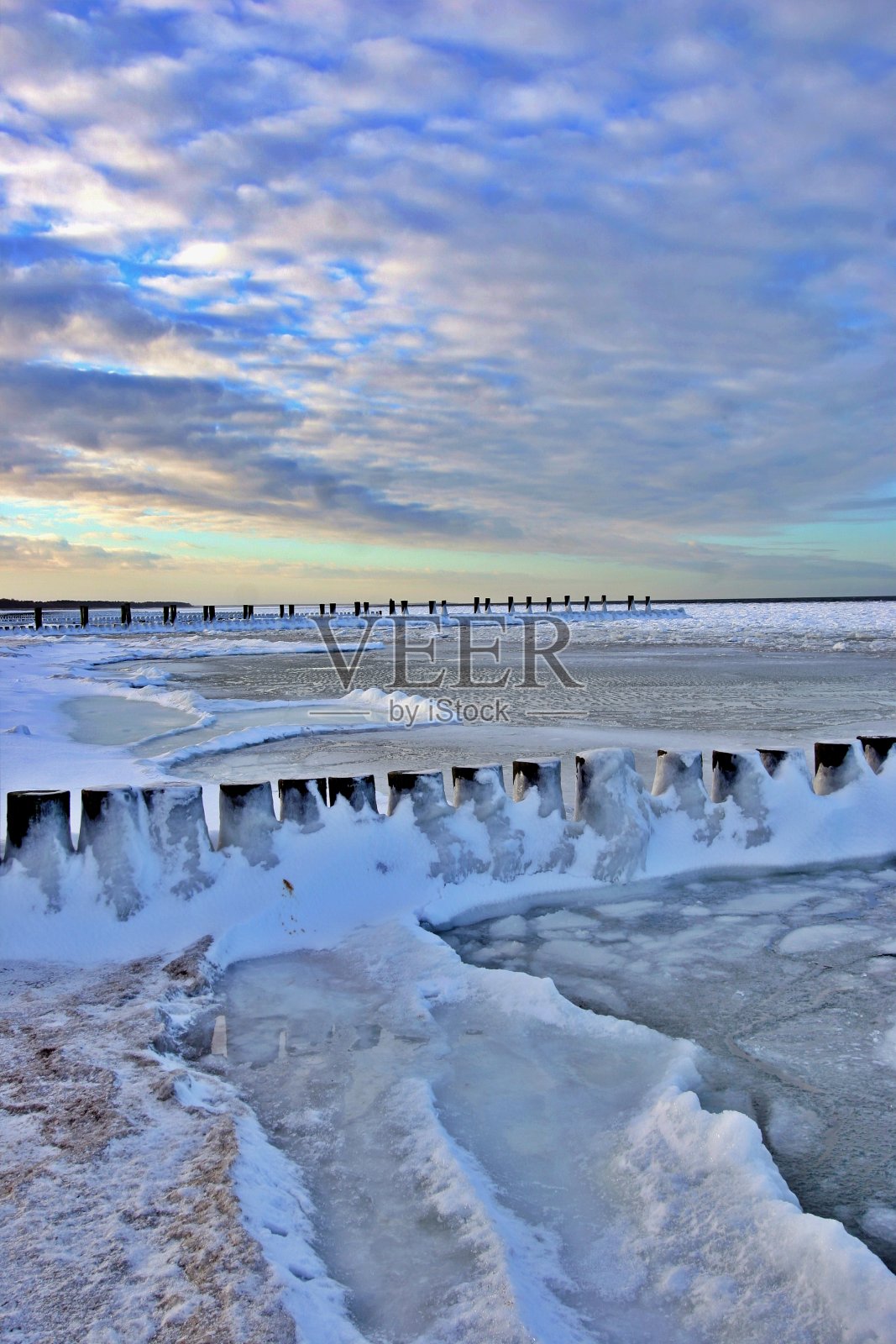雪和冰覆盖的防波堤在海边照片摄影图片