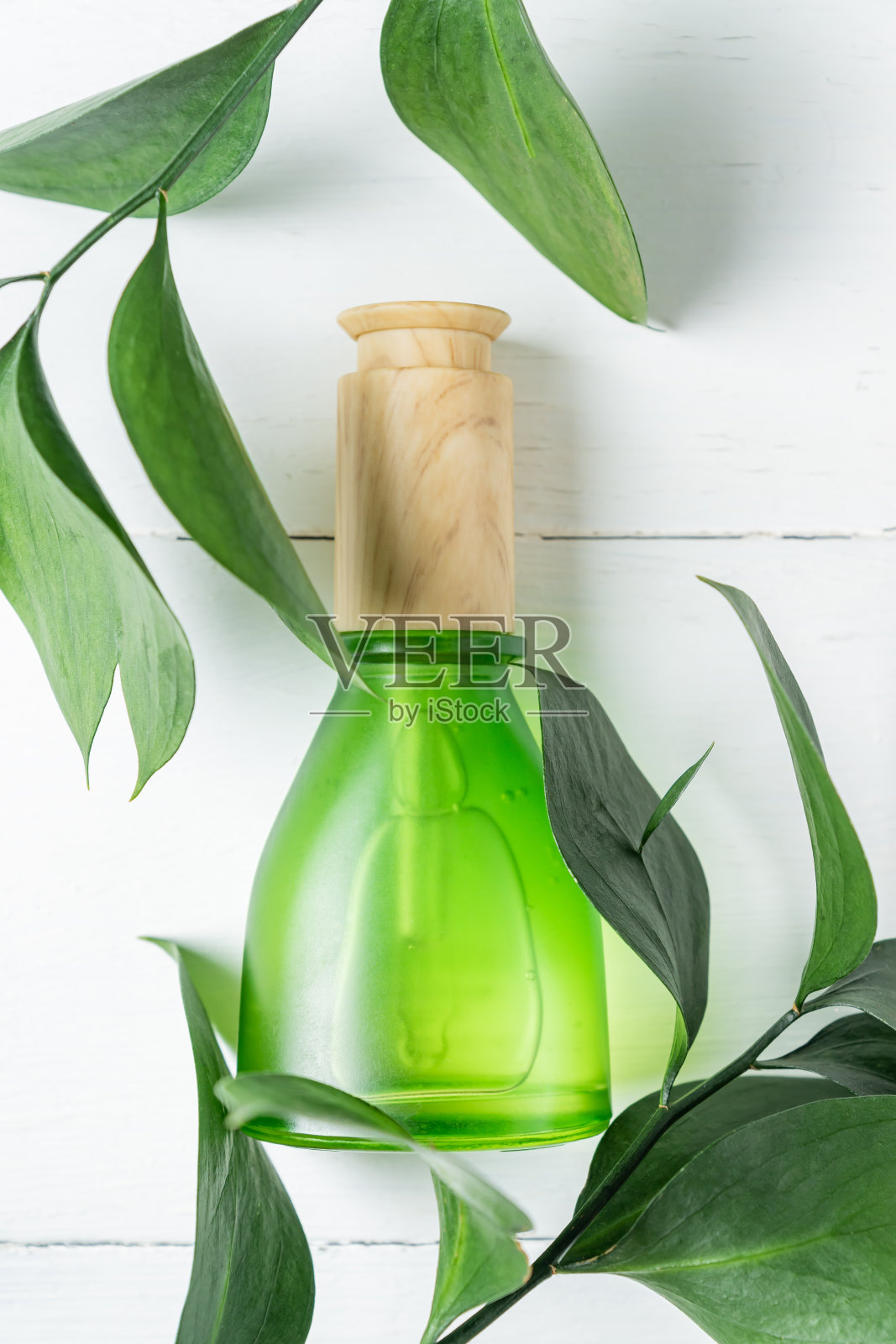 美丽和化妆品概念血清瓶和绿色叶子在白色背景，无品牌化妆品包装为您的设计。Eco的风格。照片摄影图片