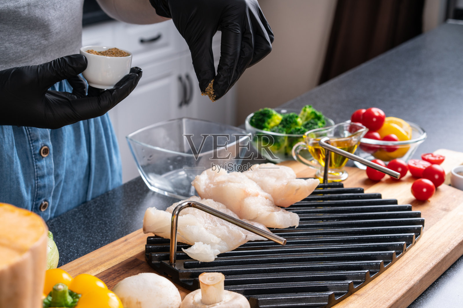 为家庭聚会做准备。在烤鱼时加入香料。照片摄影图片