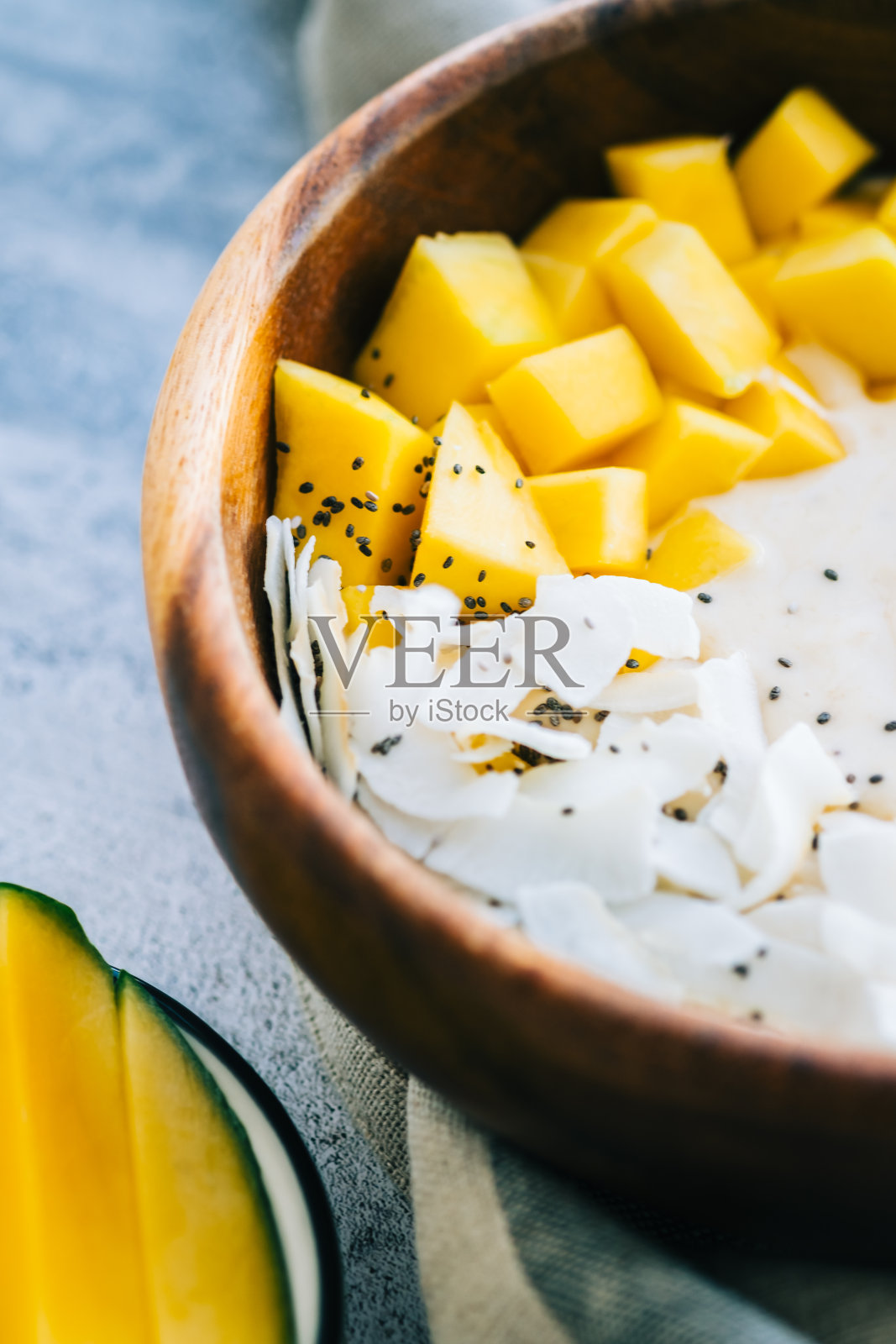 健康水果冰沙碗芒果，椰子片和奇亚籽。照片摄影图片