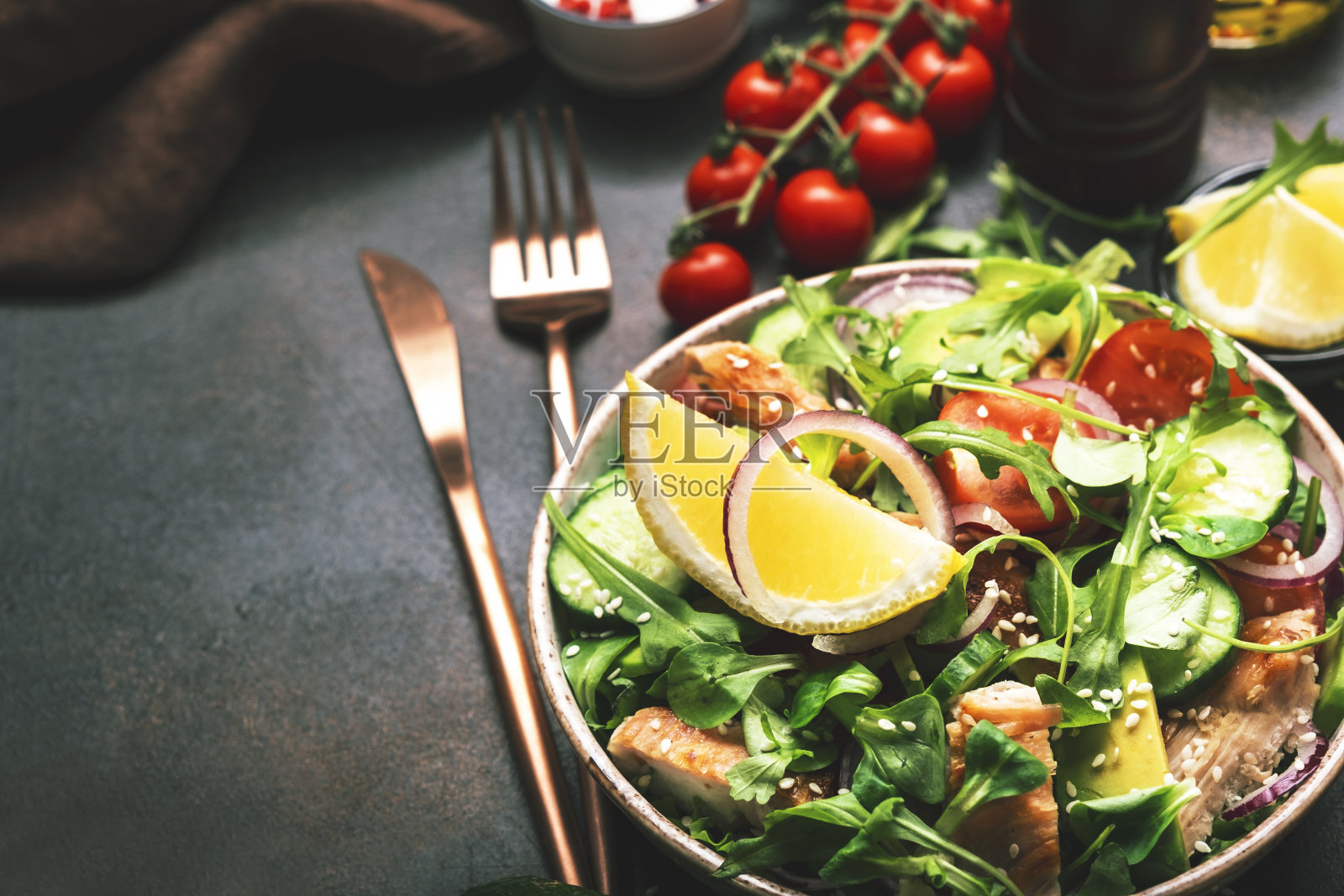 新鲜沙拉配鸡肉，番茄，芝麻，洋葱，鳄梨，芝麻和柠檬油。健康食品。前视图。棕色的桌子照片摄影图片