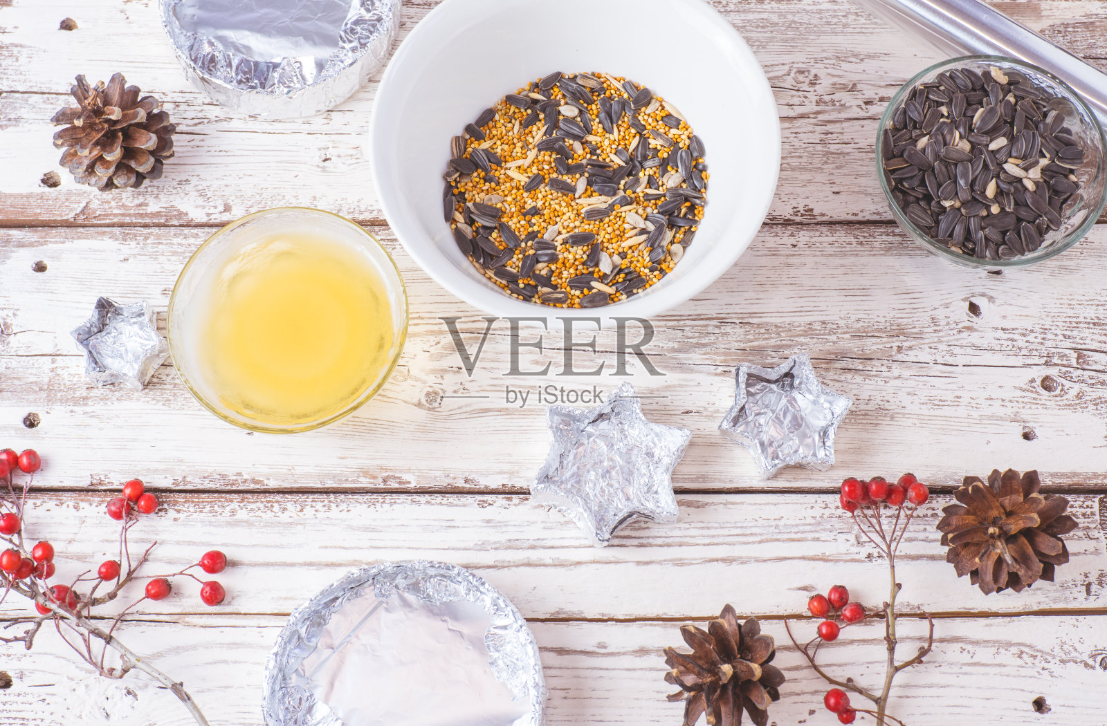 鸟类过冬的食物。种子，小米，坚果，酥油在一个碗里做喂食器在木制的白色背景上。照片摄影图片