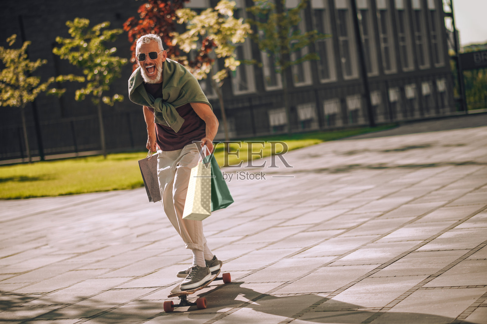激动的白发大胡子白种人在外面玩滑板照片摄影图片