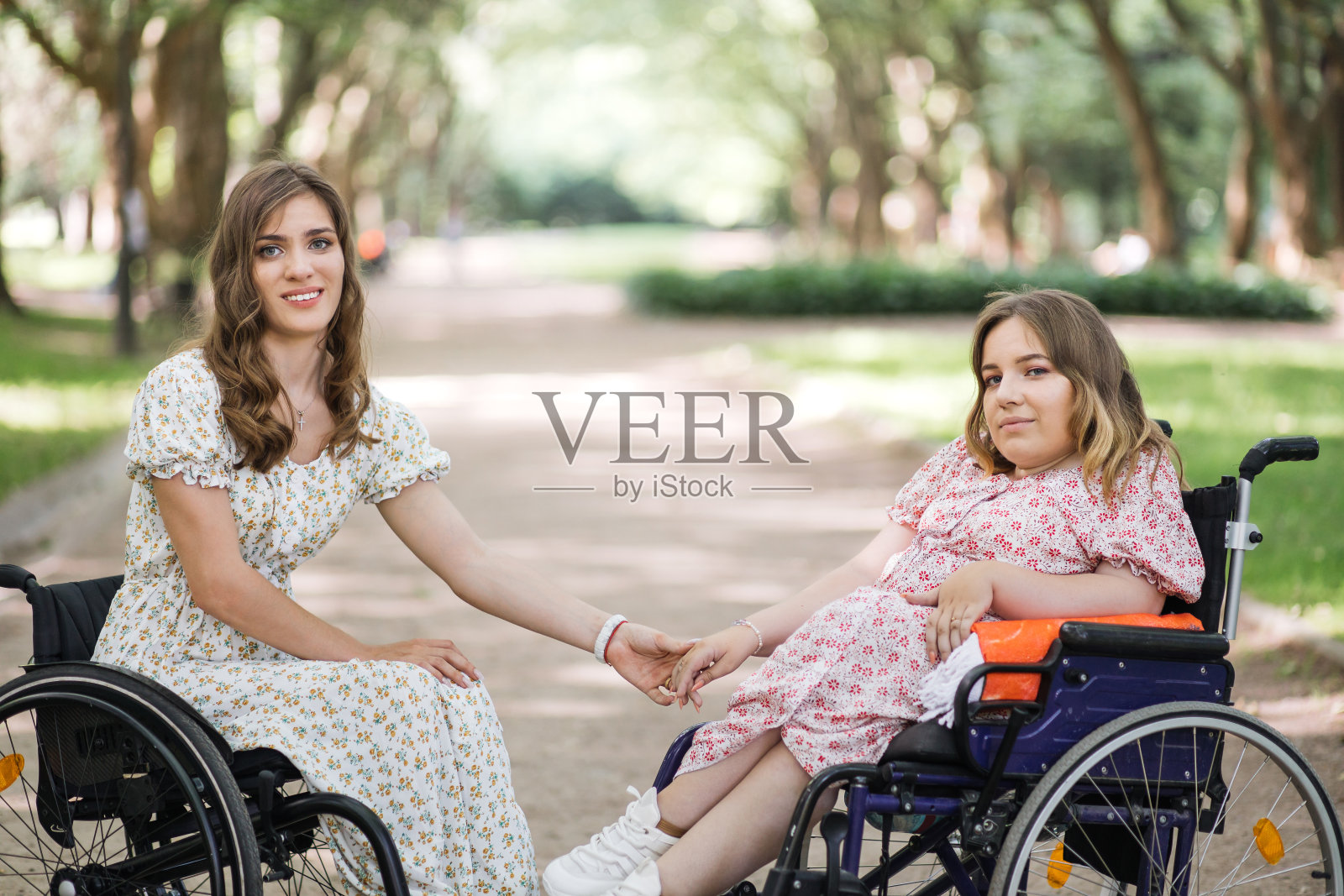 在公园里，坐在轮椅上手牵着手微笑的女人照片摄影图片