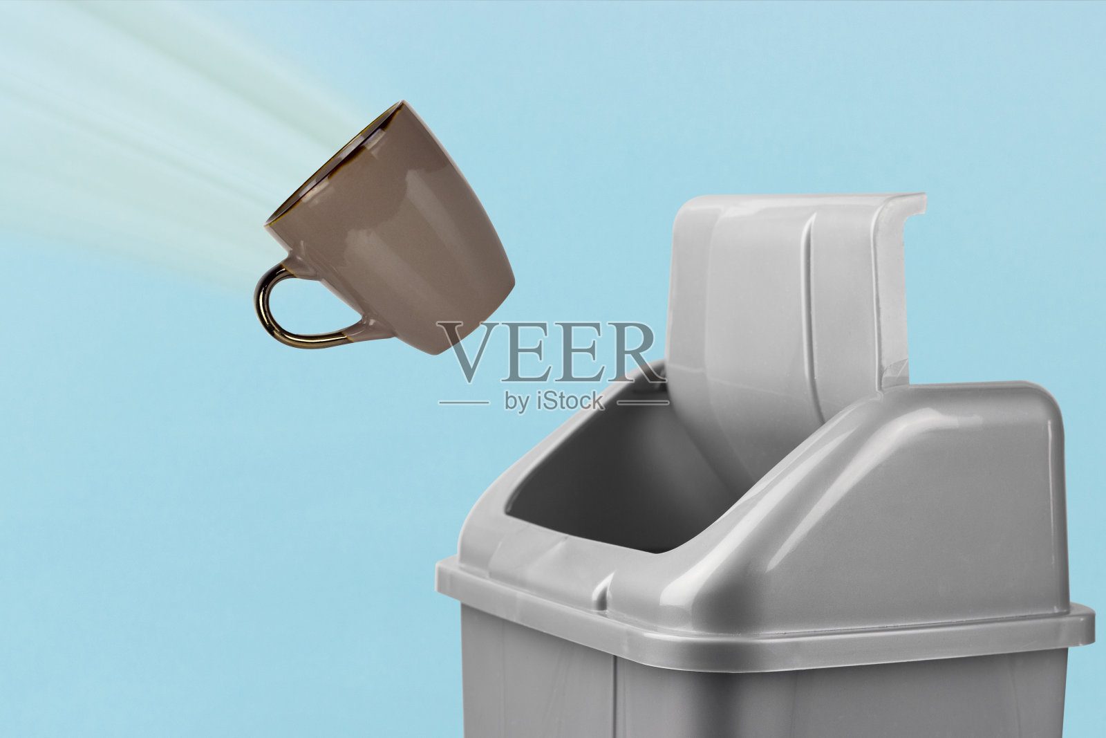 把杯子扔进垃圾桶，灰色的桶放在蓝色的背景上，糟糕的早晨概念照片摄影图片