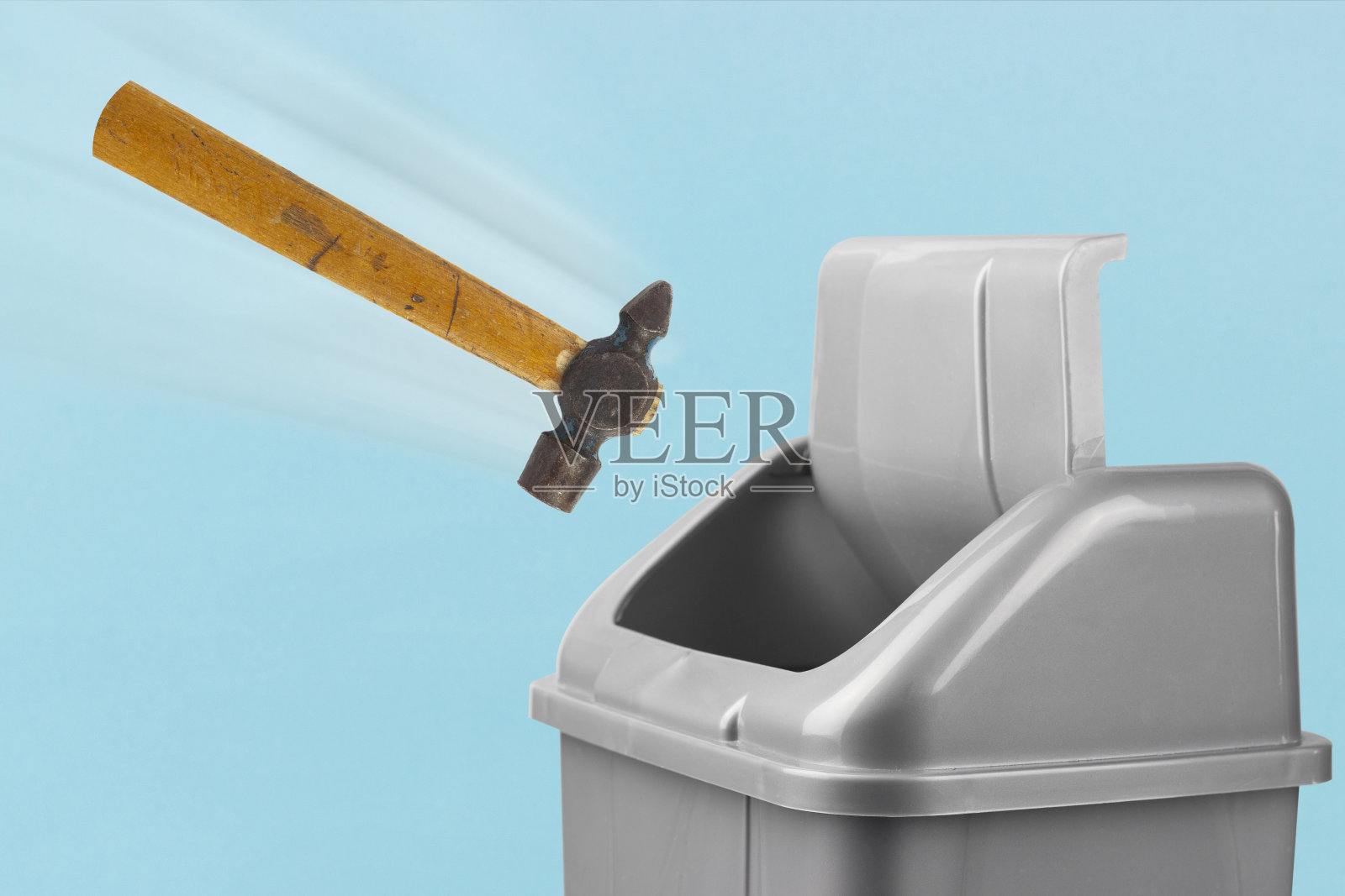 把锤子扔进垃圾桶，灰色的桶放在蓝色的背景上，这是一个失败或完成修复的概念照片摄影图片