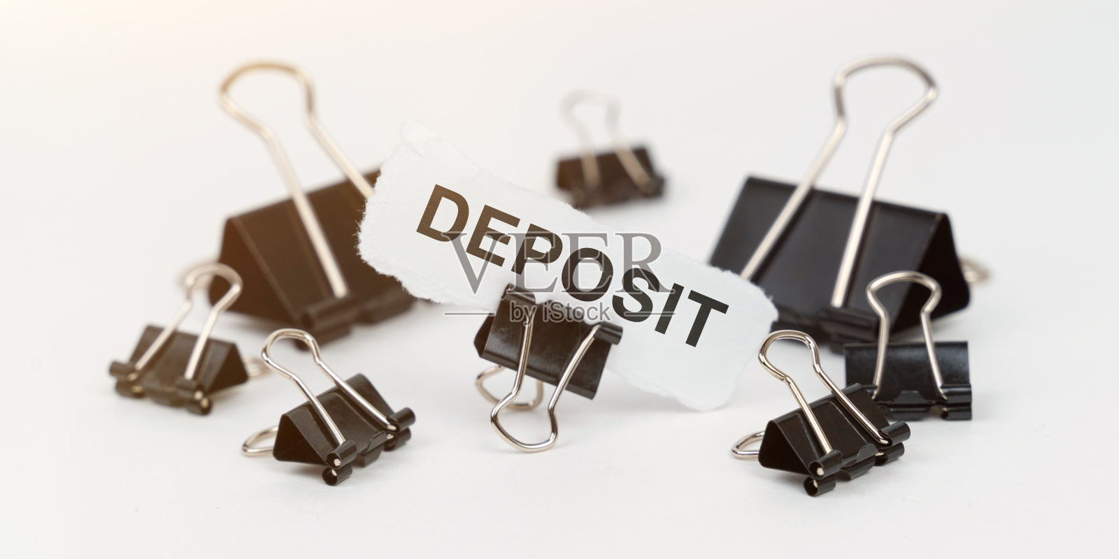 在一张白色的桌子上有办公用的夹子，在一个夹子里有一张写着“存款”的纸照片摄影图片