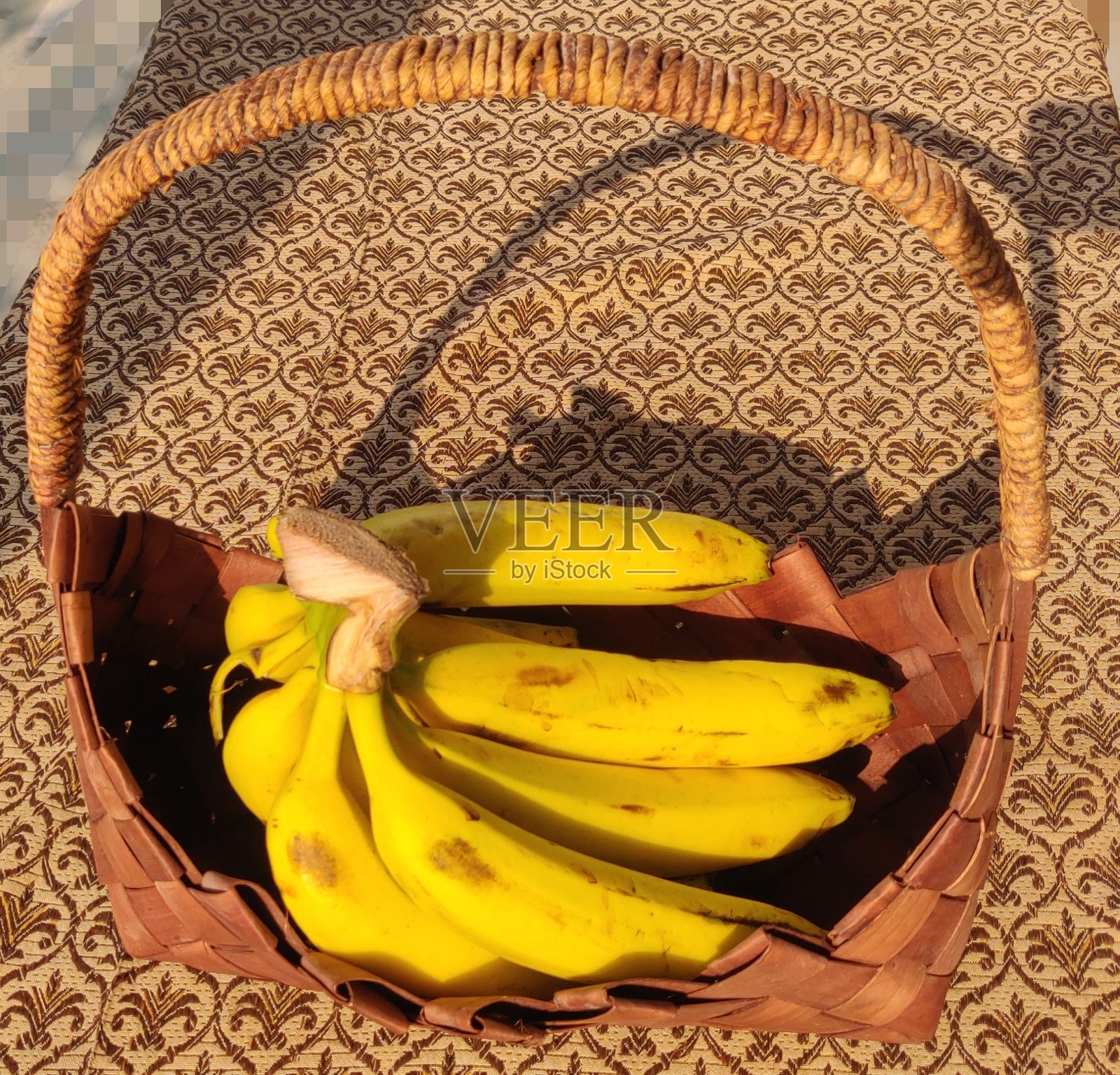 在五颜六色的背景下，篮子里有美味的成熟香蕉照片摄影图片