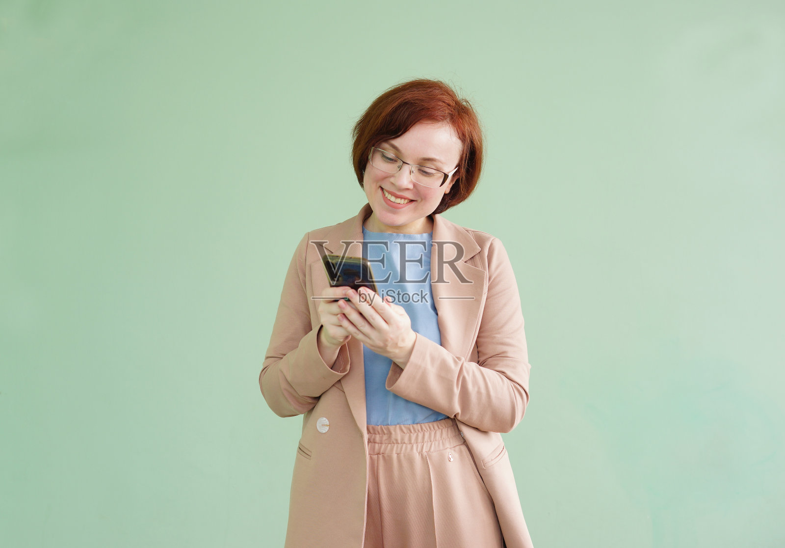 手里拿着手机的女人。微笑的脸。照片摄影图片