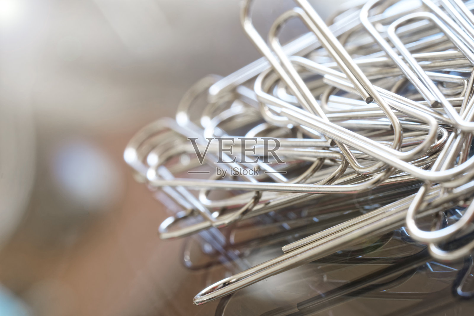 金属回形针放在反射玻璃表面上。办公室工作的概念。宏。有选择性的重点。为碑文留出空间。照片摄影图片