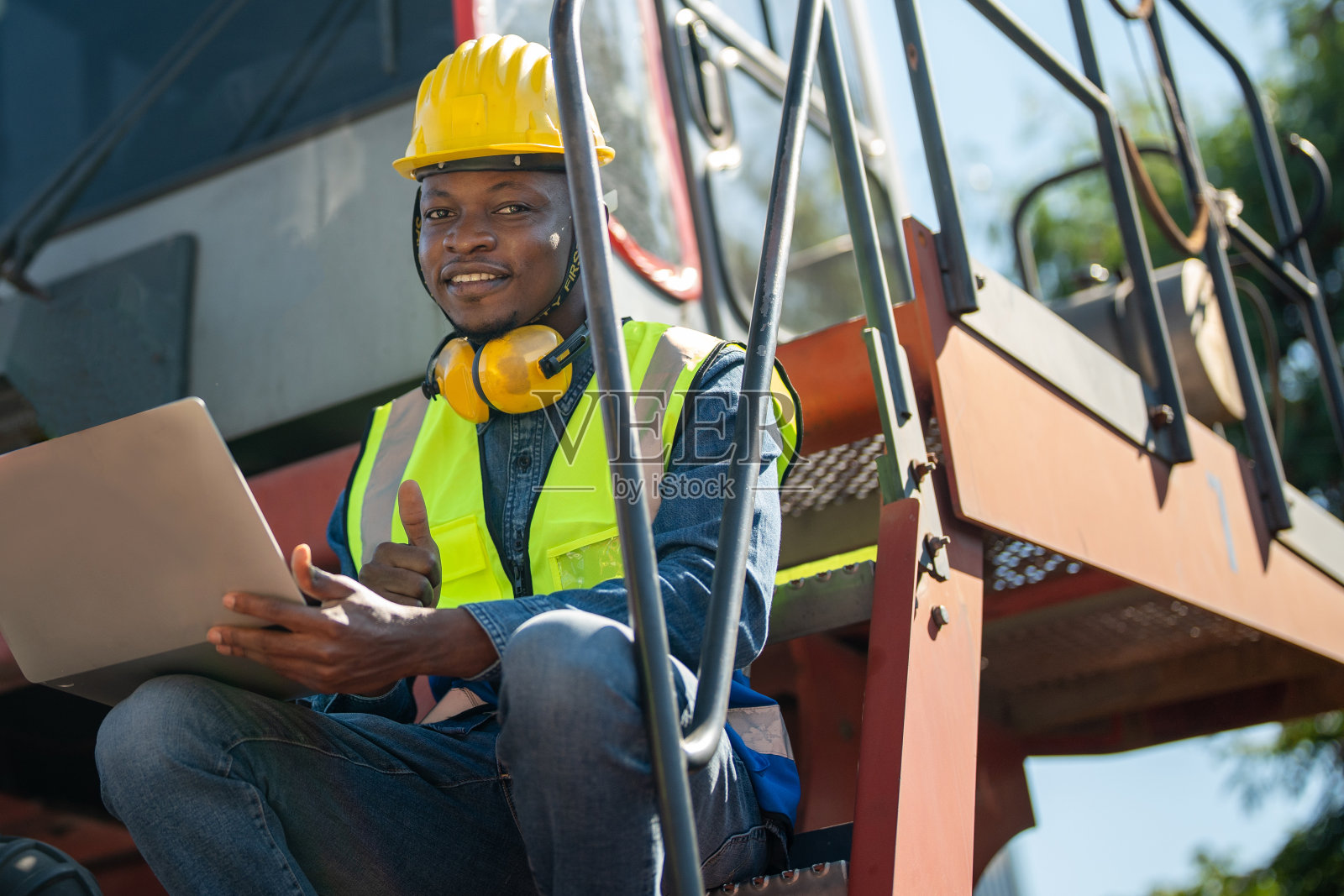 非洲工人、工程师、技术员手持手提电脑检查重型机械发动机。修理重工业机械零件的工头。照片摄影图片