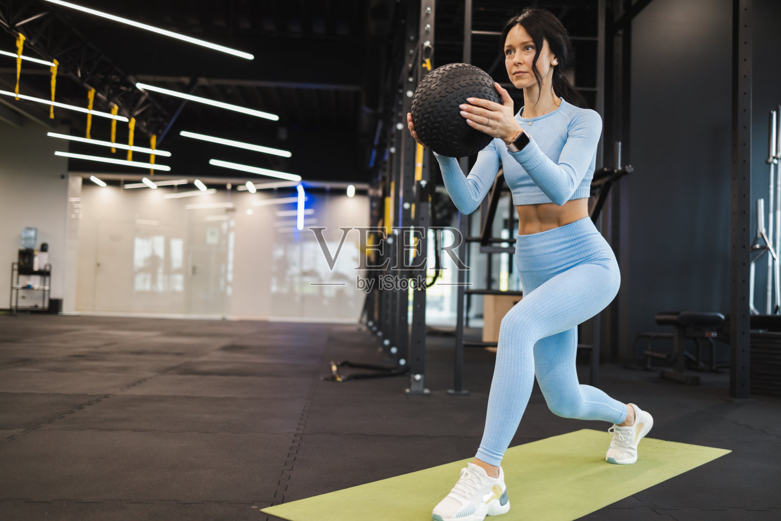 女运动员用实心球猛冲。健身女孩用健身球做腿部锻炼照片摄影图片