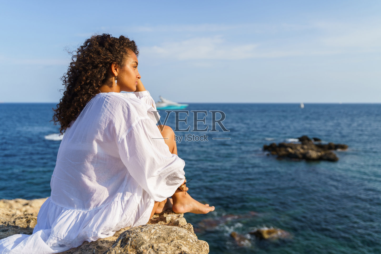 卷发的女人坐着看风景。自由的概念照片摄影图片